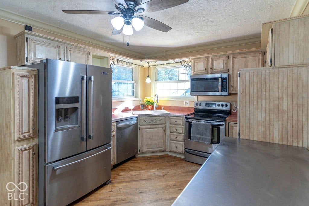 Full kitchen featuring stainless steel appliances, wood-finish flooring, and crown molding