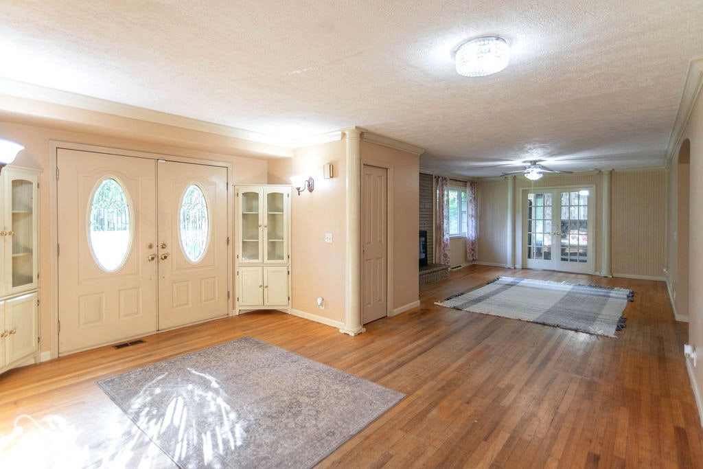 Hardwood flooring throughout, double entry doors with decorative glass inserts, built-in display cabinetry, ceiling fan, and French doors