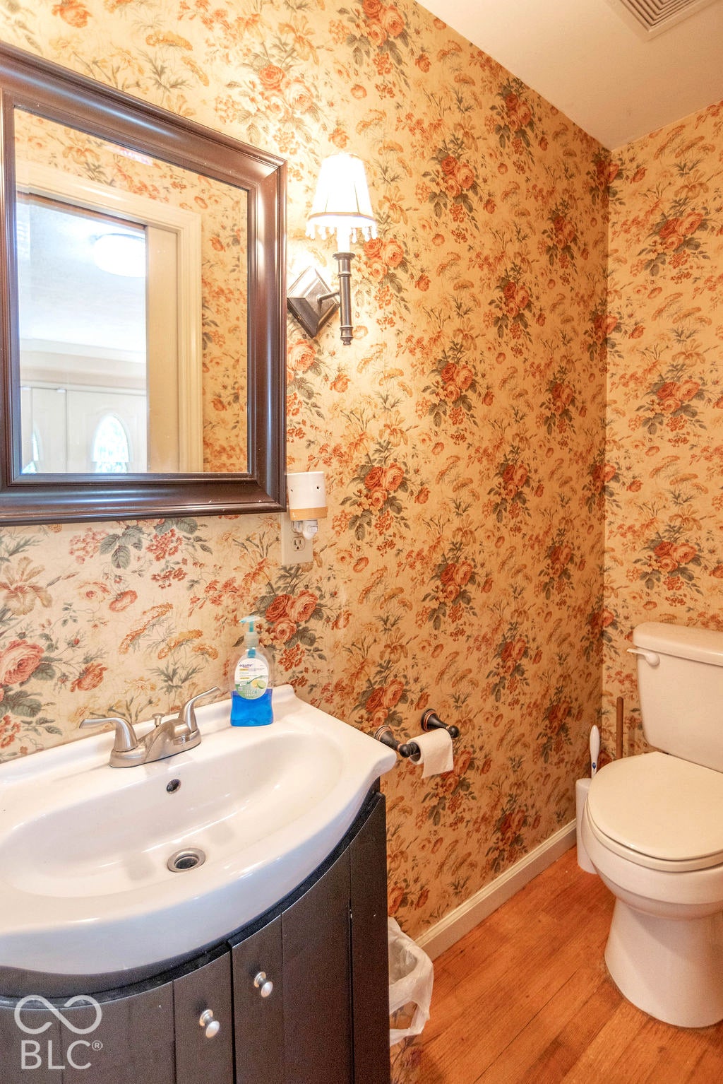 Wood-finish flooring with a white toilet and a vanity with a white basin sink