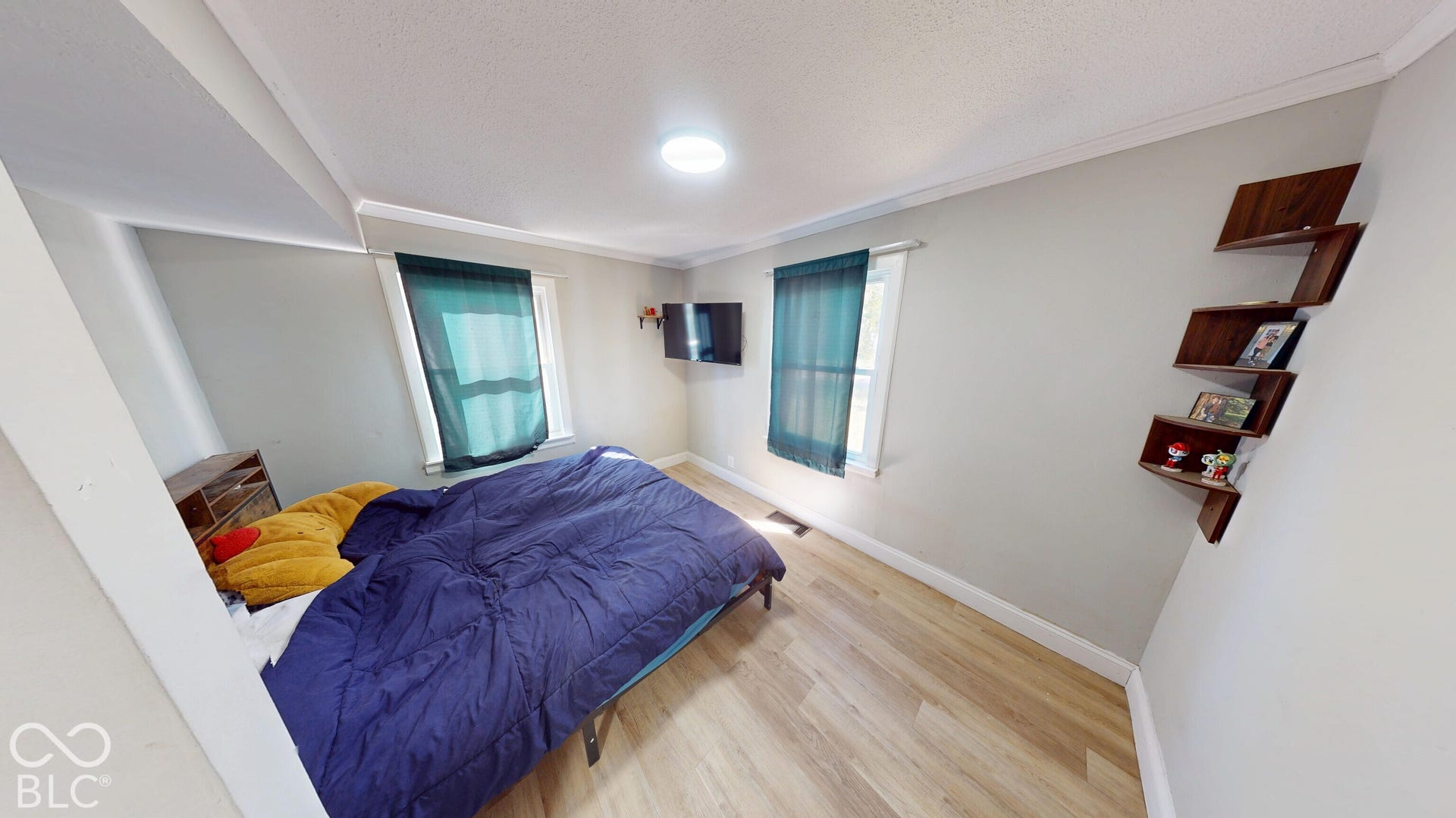 Wood-finish flooring, two windows with window treatments, built-in wall shelving, and ceiling-mounted light fixture