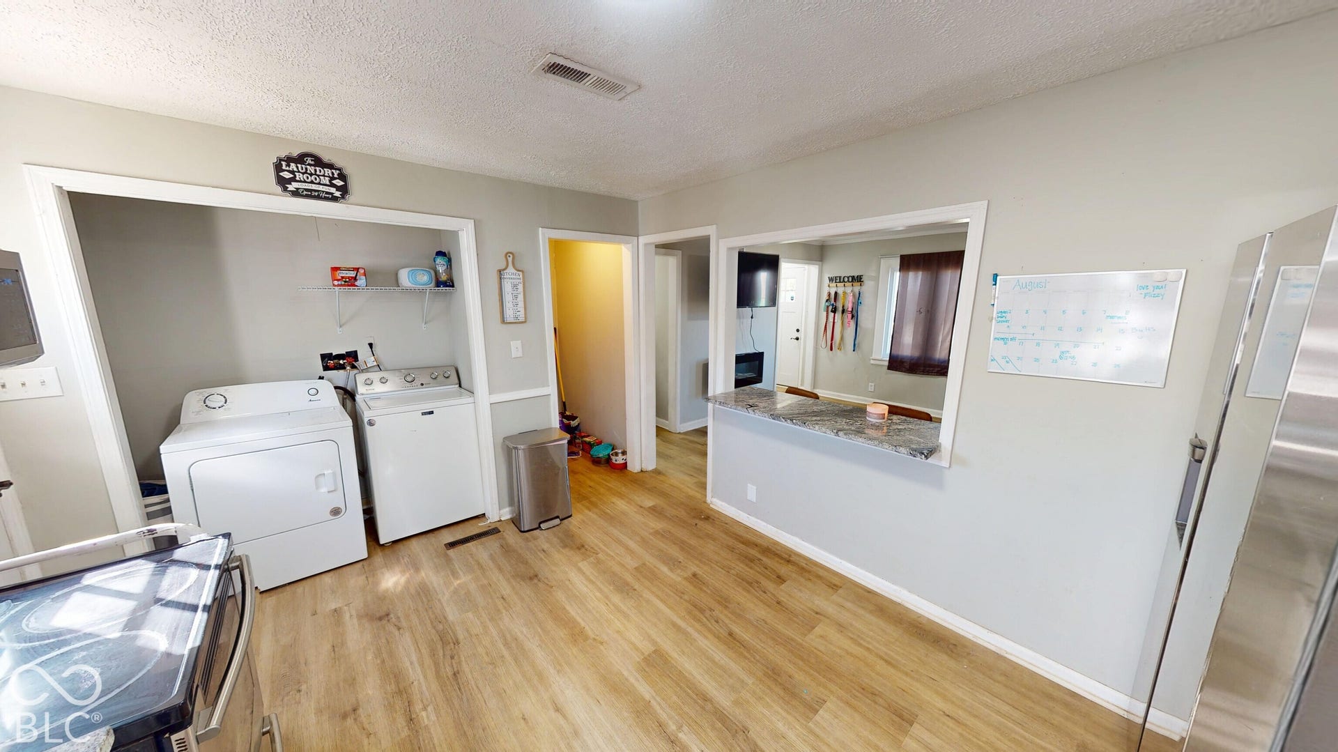 Wood-finish flooring, pass-through window with solid surface countertop, and integrated laundry area