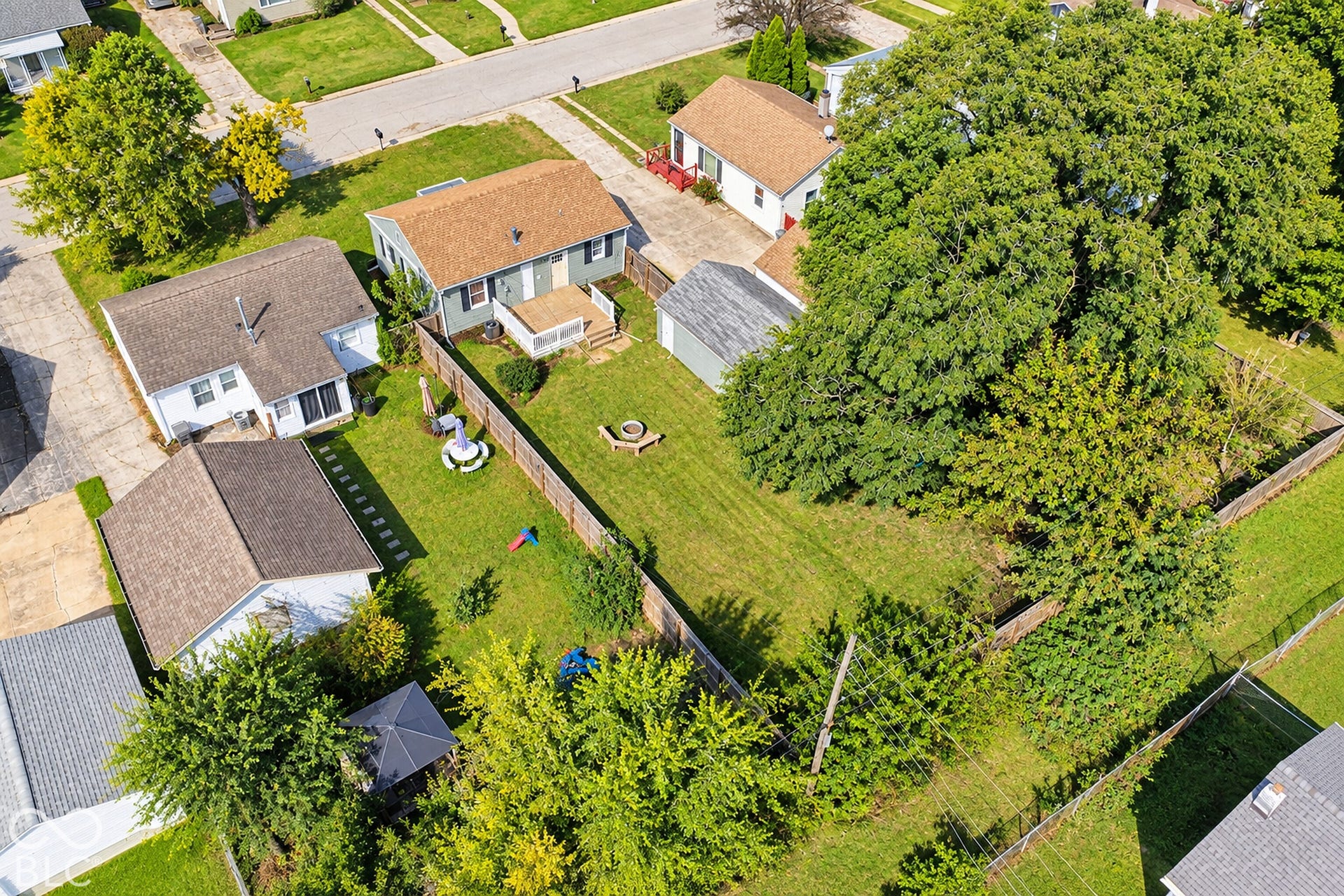 Virtually Altered - Expansive backyard featuring a manicured lawn, established trees, and a privacy fence