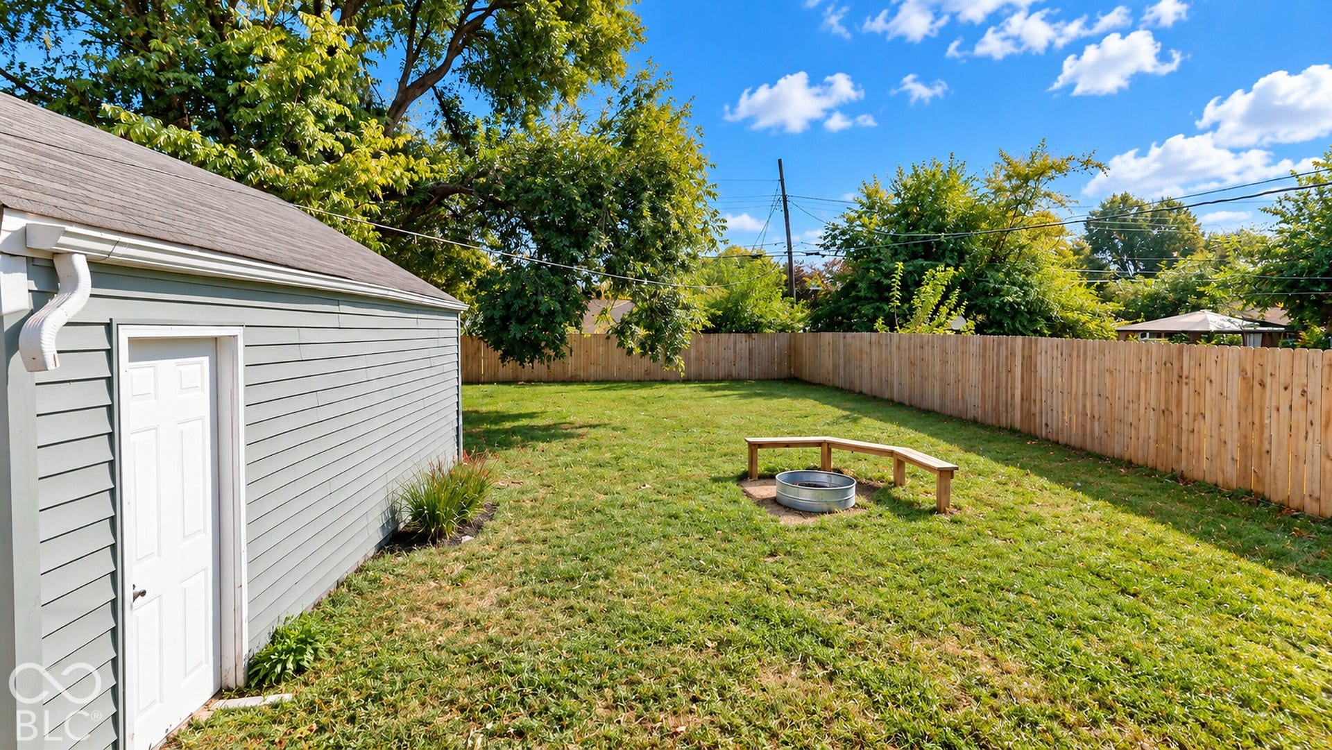 Virtually Altered - Expansive fenced yard with a detached structure featuring horizontal siding, a side entry door, and a shingle roof