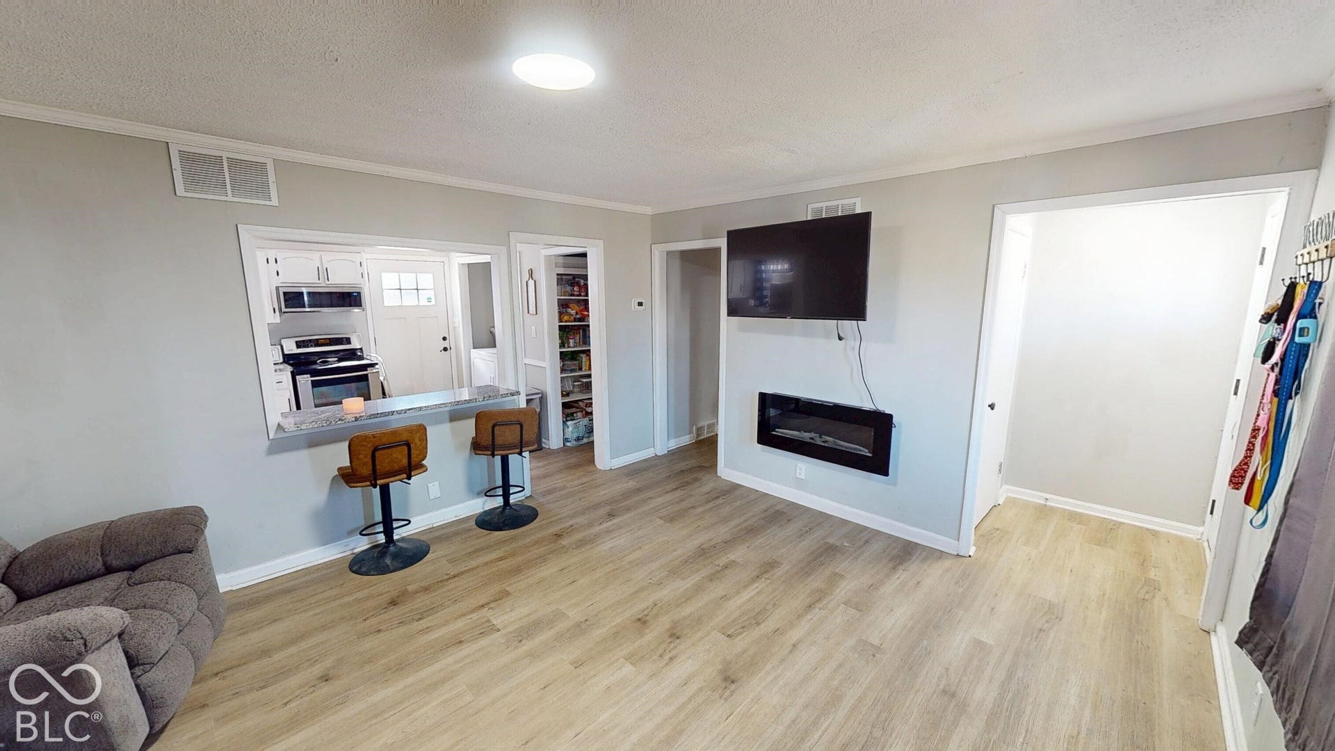 Wood-finish flooring, recessed ceiling light, built-in electric fireplace, pass-through breakfast bar, and pantry with shelving