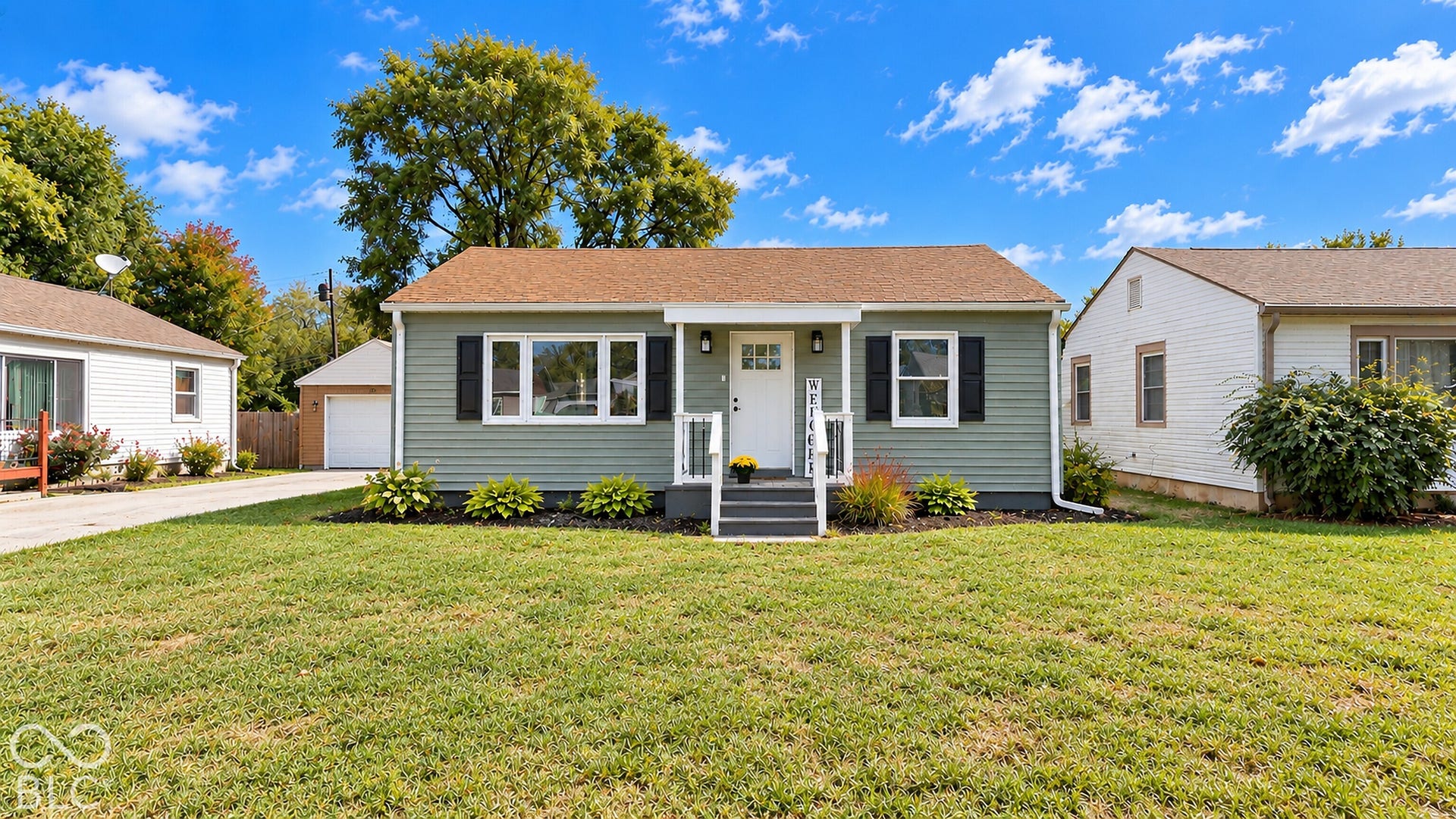 Virtually Altered - Green siding exterior with a white front door, dark gray front steps, white porch railing, and black window shutters
