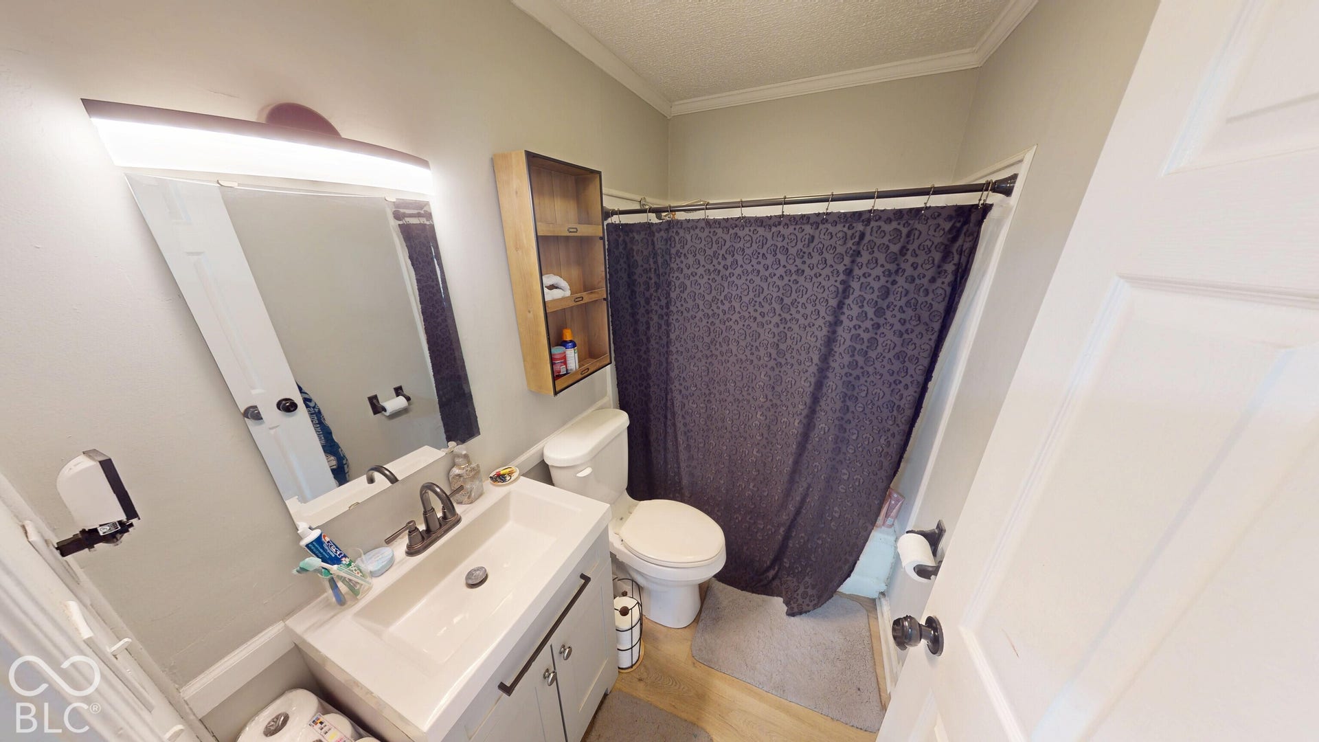 Bathroom featuring a single vanity with storage, wall-mounted mirror with integrated lighting, and a combination shower/tub