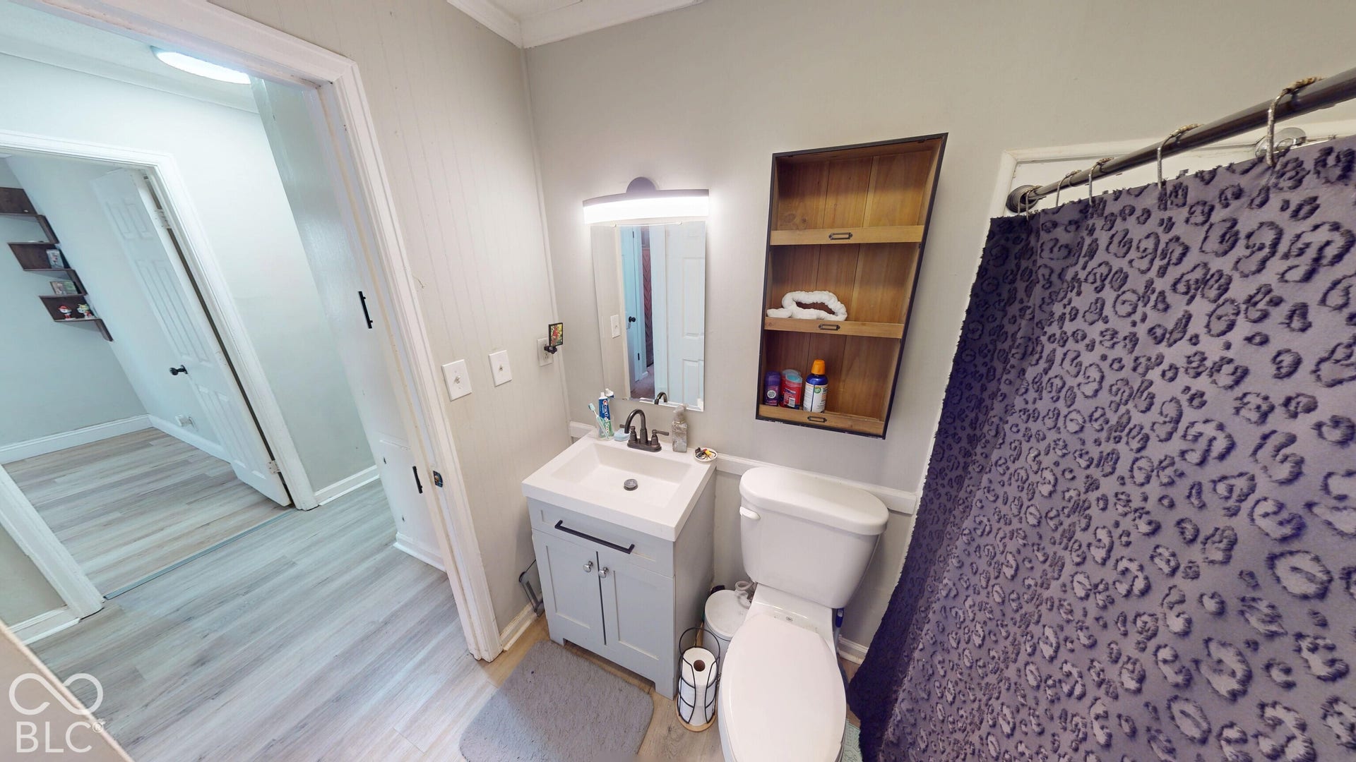 Bathroom featuring a single vanity, built-in shelving, and light wood-finish flooring