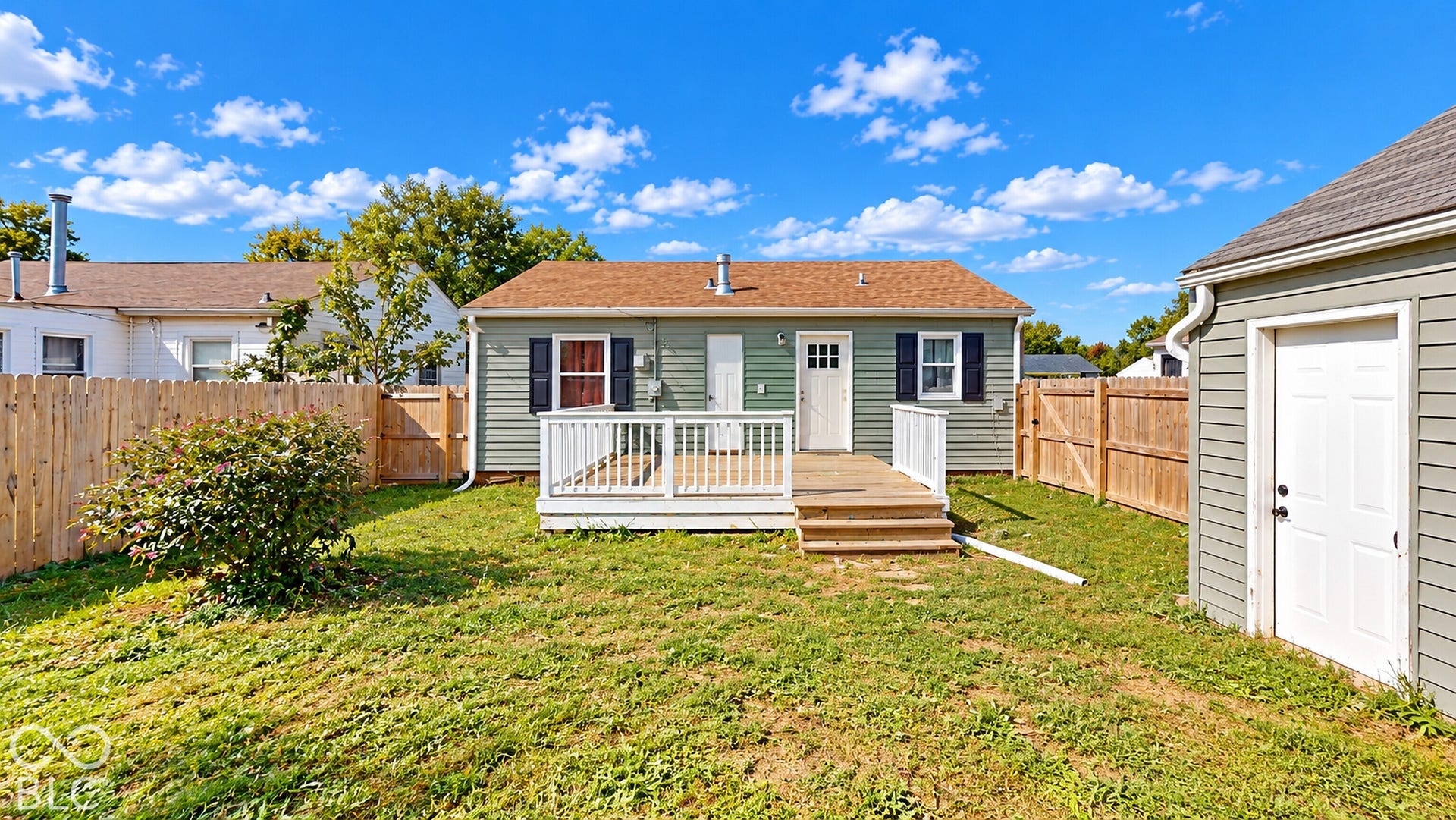Virtually Altered - Rear exterior with a wooden deck, a wooden privacy fence, and a garage
