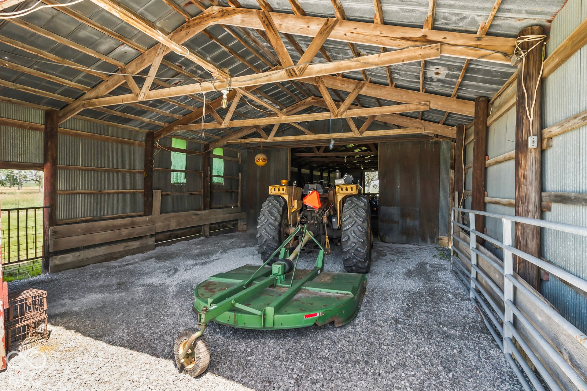 10954 N County Road 150 Road E, Pittsboro, IN 46167 Covered outbuilding featuring exposed timber trusses, corrugated metal wall panels, gravel flooring, and integrated metal livestock fencing