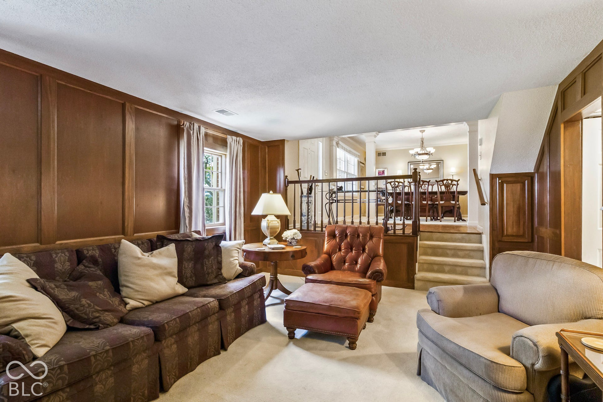 10954 N County Road 150 Road E, Pittsboro, IN 46167 Living area featuring extensive wood wall paneling, tiered levels with carpeted stairs, and decorative wood railings