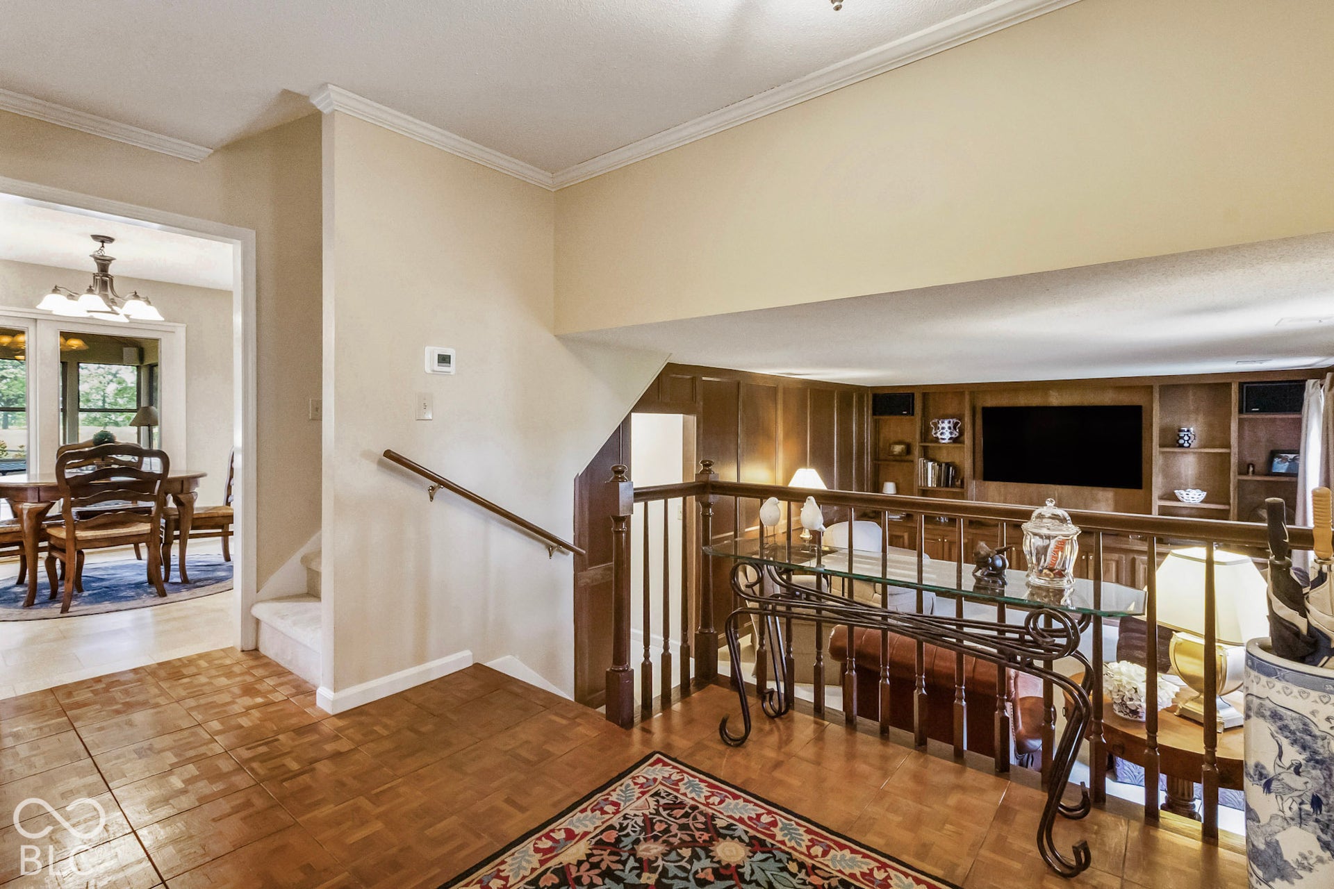 10954 N County Road 150 Road E, Pittsboro, IN 46167 Parquet wood flooring, wood-paneled walls, built-in shelving, and a wooden stair railing with balusters