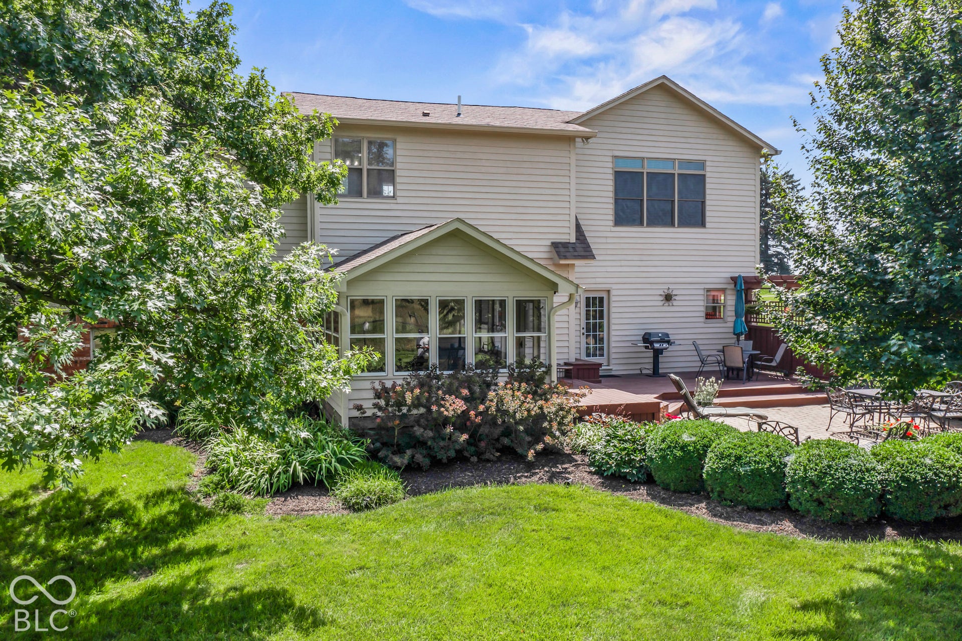 10954 N County Road 150 Road E, Pittsboro, IN 46167 Two-story residence featuring light-toned vinyl siding, a multi-windowed sunroom, a composite deck, a paver patio, and mature landscaping