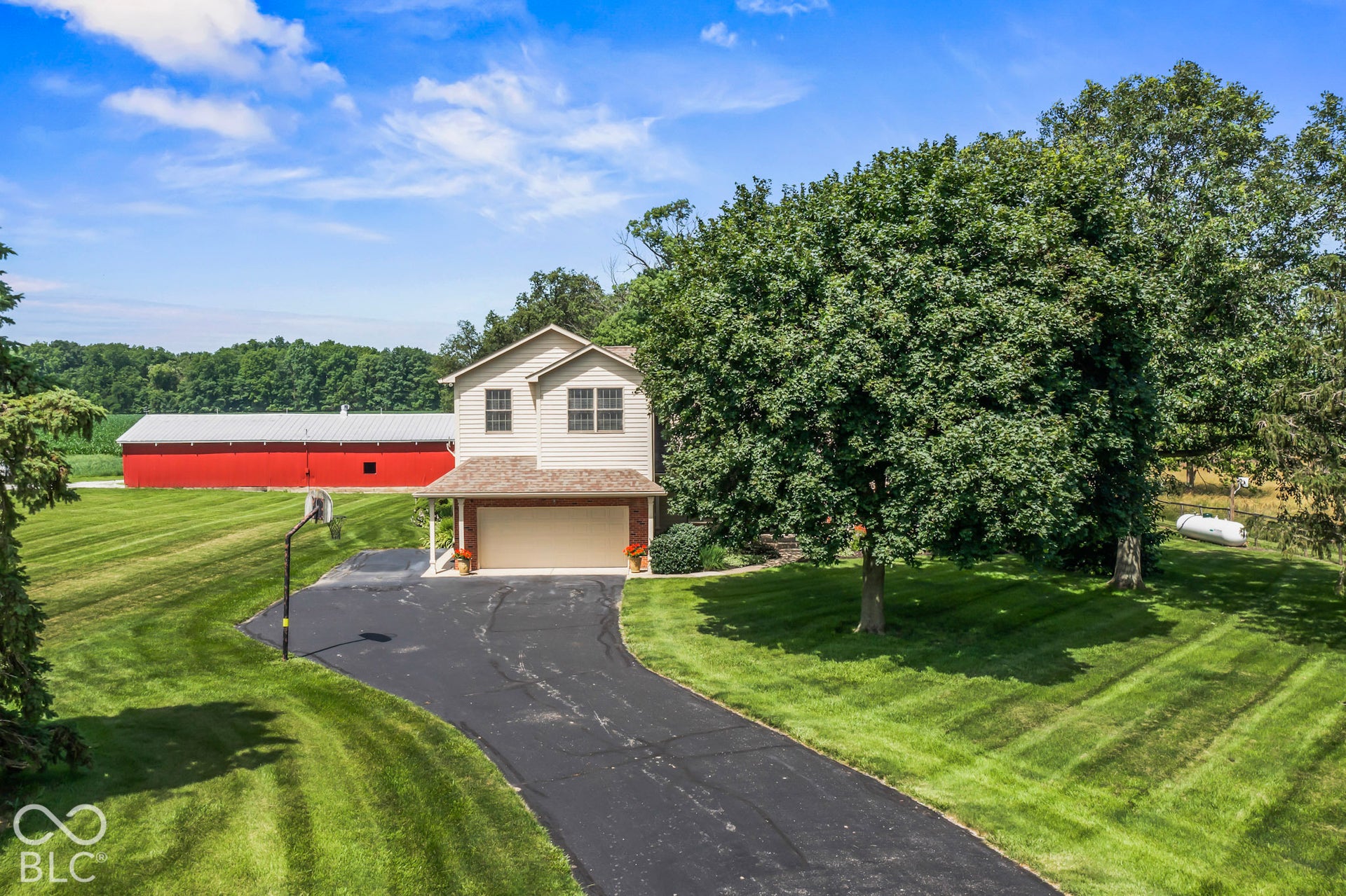 10954 N County Road 150 Road E, Pittsboro, IN 46167 Two-story home with horizontal siding, attached two-car garage, asphalt driveway, and large red pole barn on expansive acreage