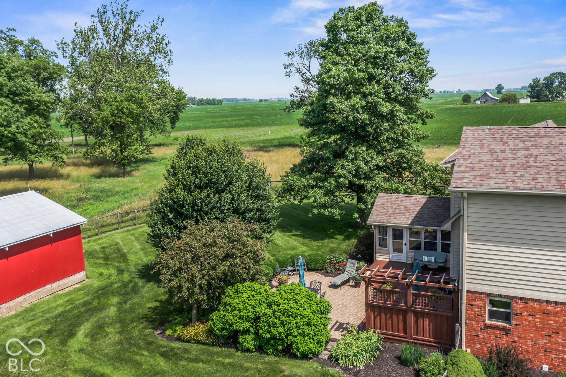 10954 N County Road 150 Road E, Pittsboro, IN 46167 Exterior grounds featuring a paved patio, wooden pergola, mature trees, manicured lawn, and an auxiliary structure