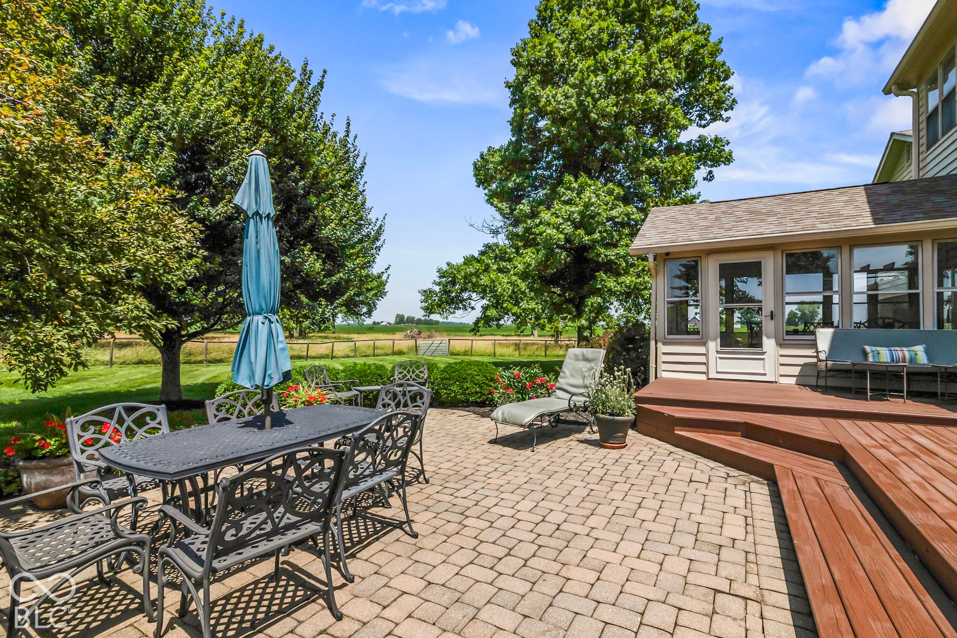 10954 N County Road 150 Road E, Pittsboro, IN 46167 Paver patio featuring a multi-level wood-finish deck, enclosed sunroom, and expansive lawn with mature trees