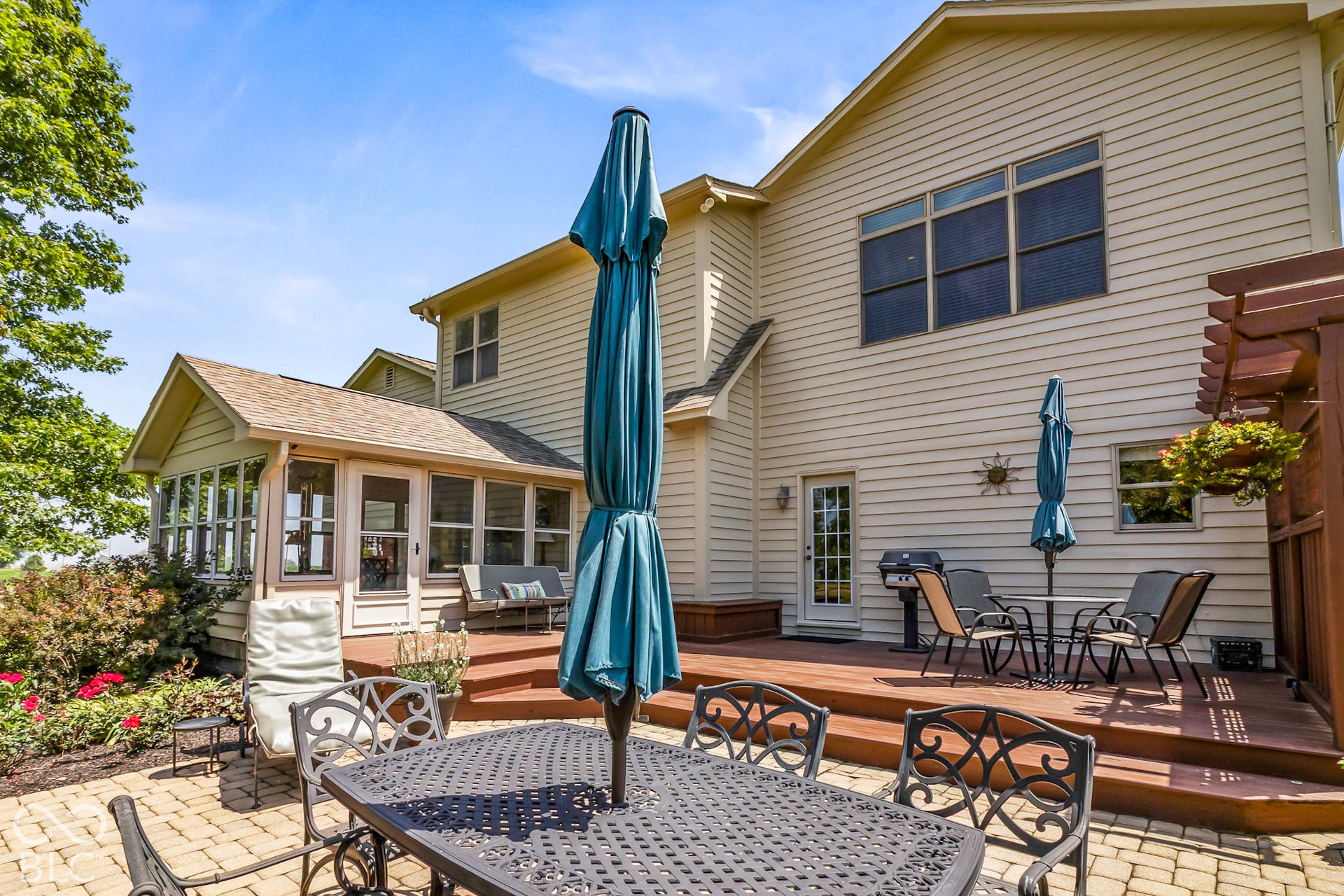 10954 N County Road 150 Road E, Pittsboro, IN 46167 Multi-level rear exterior featuring a paved stone patio, an expansive elevated wood deck, a sunroom with large windows, and a built-in wooden pergola