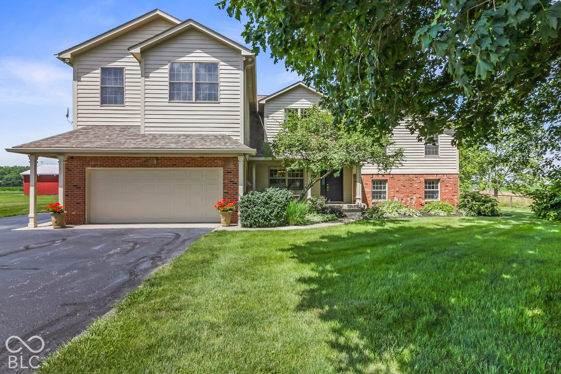 10954 N County Road 150 Road E, Pittsboro, IN 46167 Two-story exterior featuring tan horizontal siding, red brick masonry, a multi-car garage, and asphalt driveway