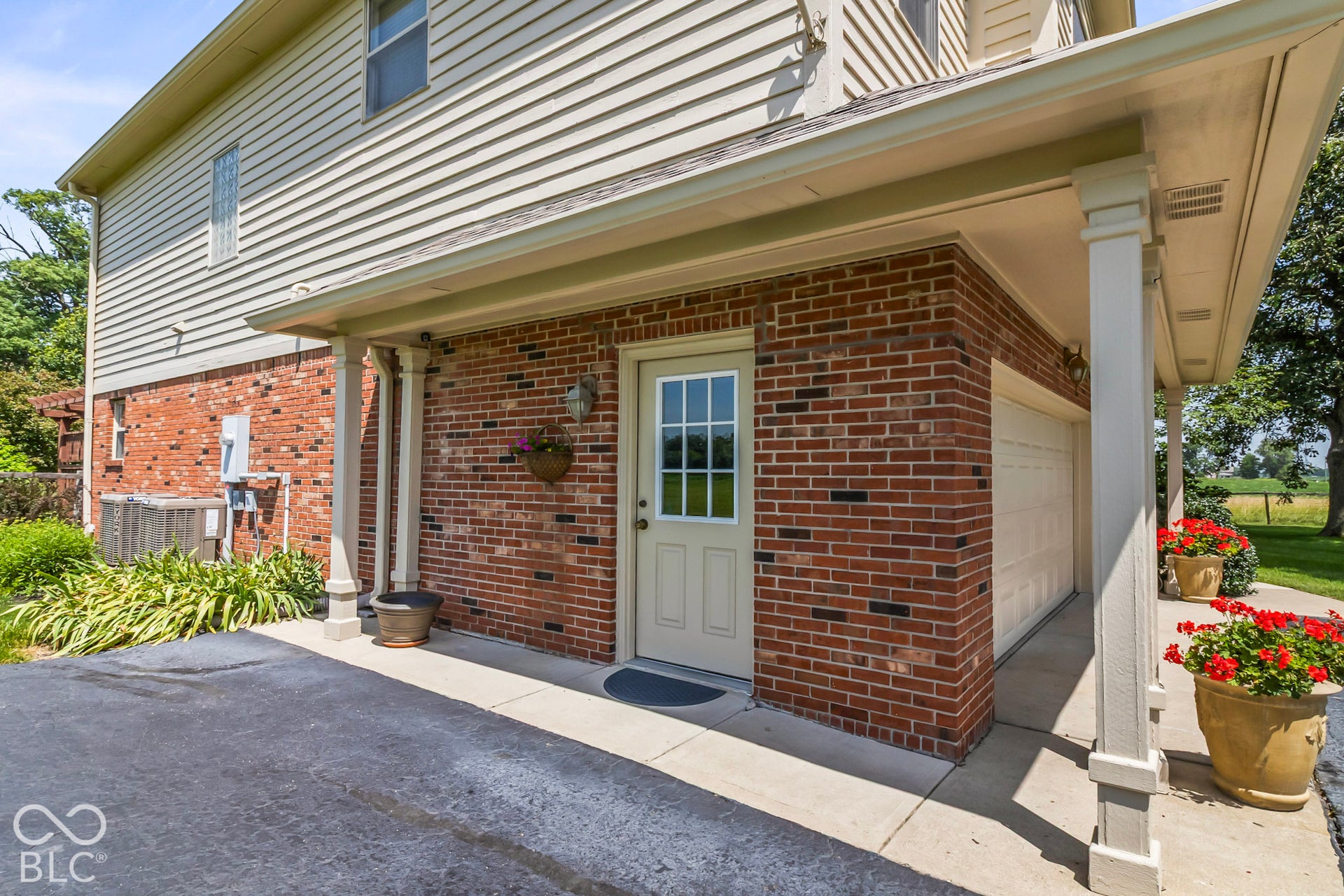 10954 N County Road 150 Road E, Pittsboro, IN 46167 Exterior featuring a red brick facade, covered concrete porch with square columns, and a garage with a multi-pane glass entry door
