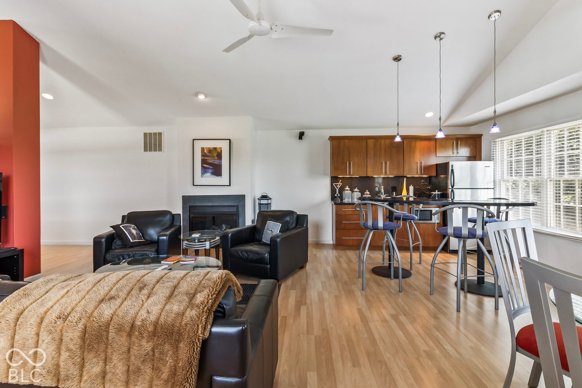 10954 N County Road 150 Road E, Pittsboro, IN 46167 Vaulted ceilings, wood-finish flooring, fireplace with stone surround, kitchen with wood cabinetry and dark countertops, and pendant lighting