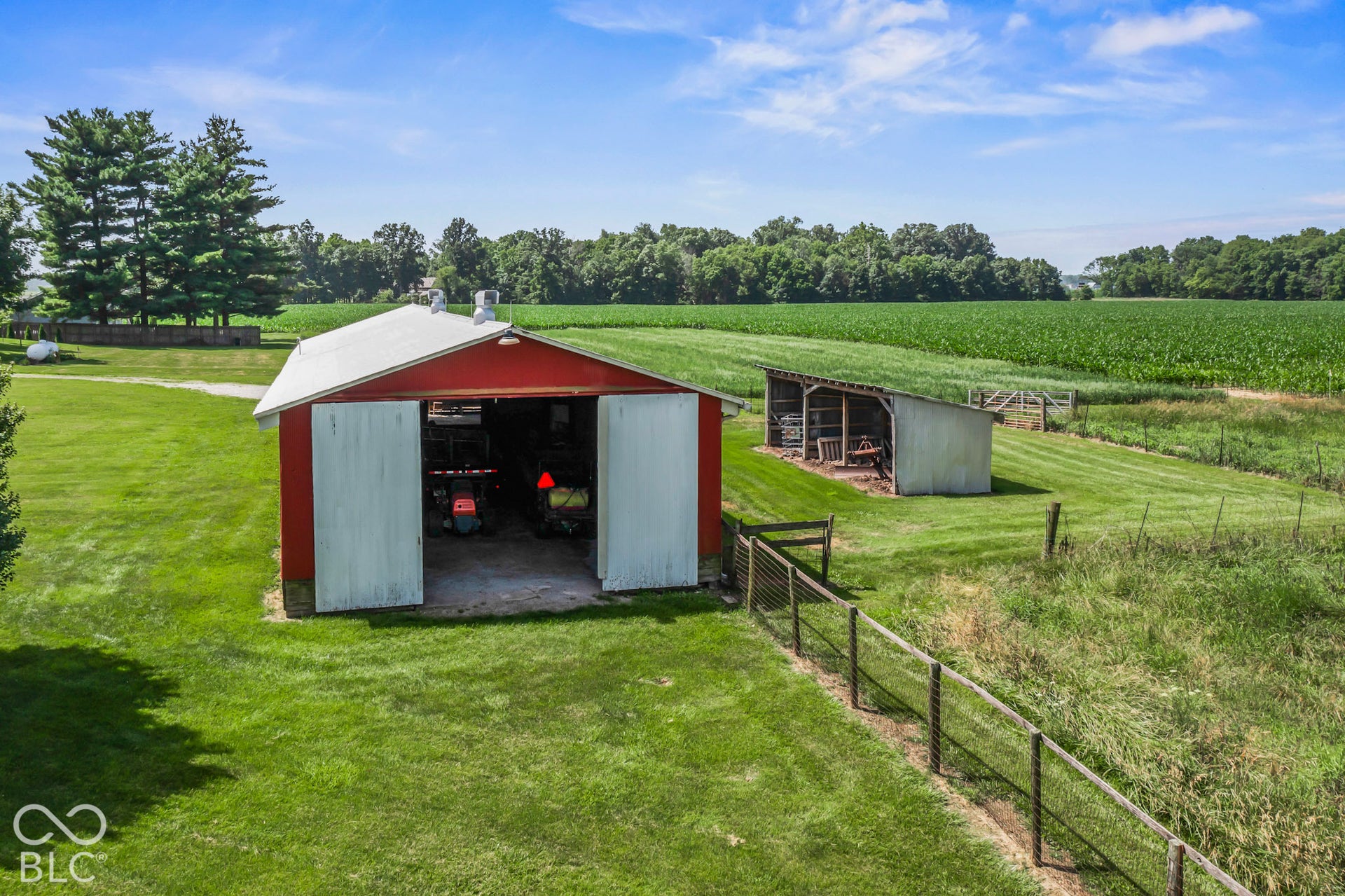 10954 N County Road 150 Road E, Pittsboro, IN 46167 Outbuilding with white sliding doors, metal roof, open-sided lean-to, and wire fencing on expansive acreage