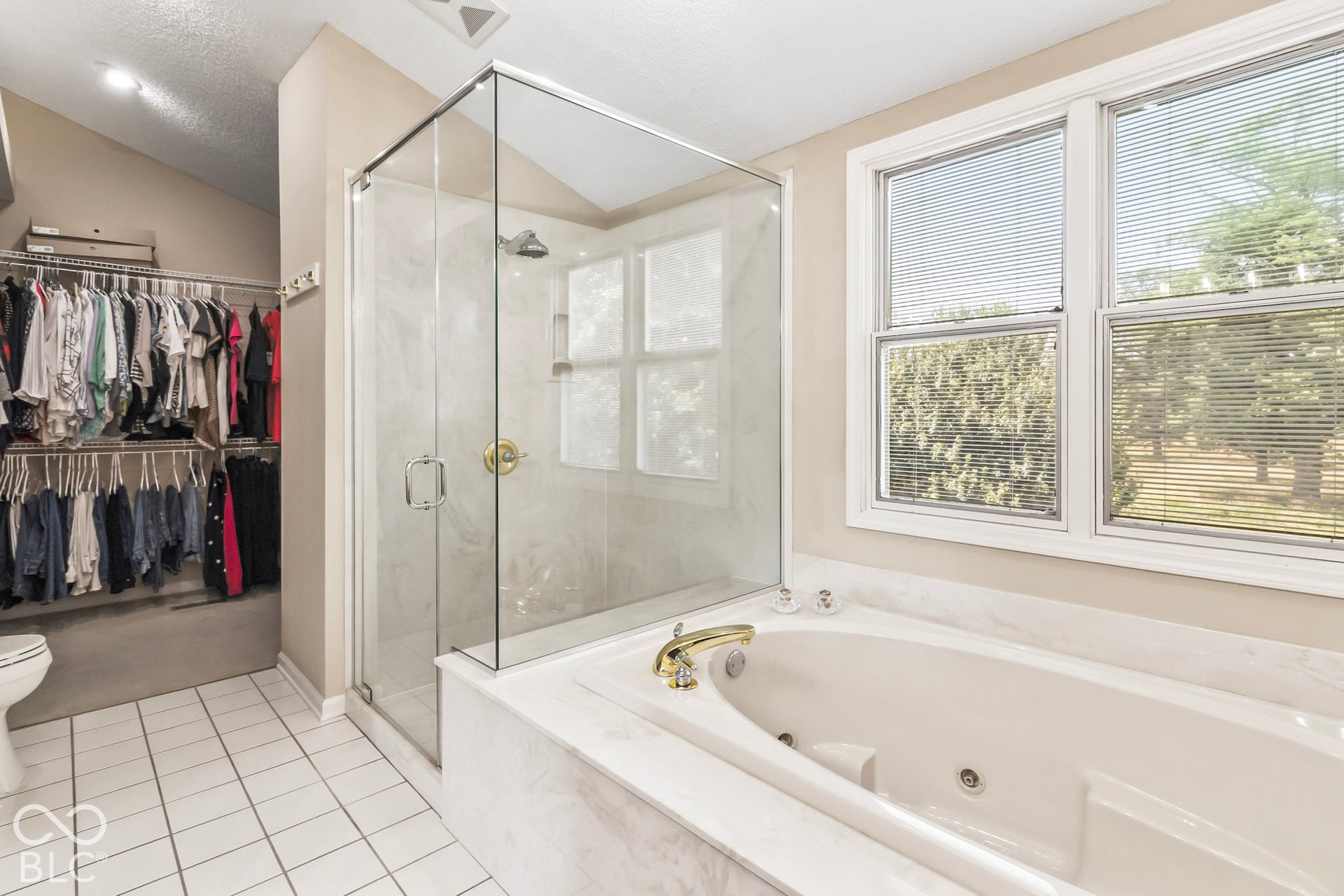 10954 N County Road 150 Road E, Pittsboro, IN 46167 Jetted soaking tub with stone-finish surround, glass-enclosed shower, walk-in closet with built-in shelving, and ceramic tile flooring