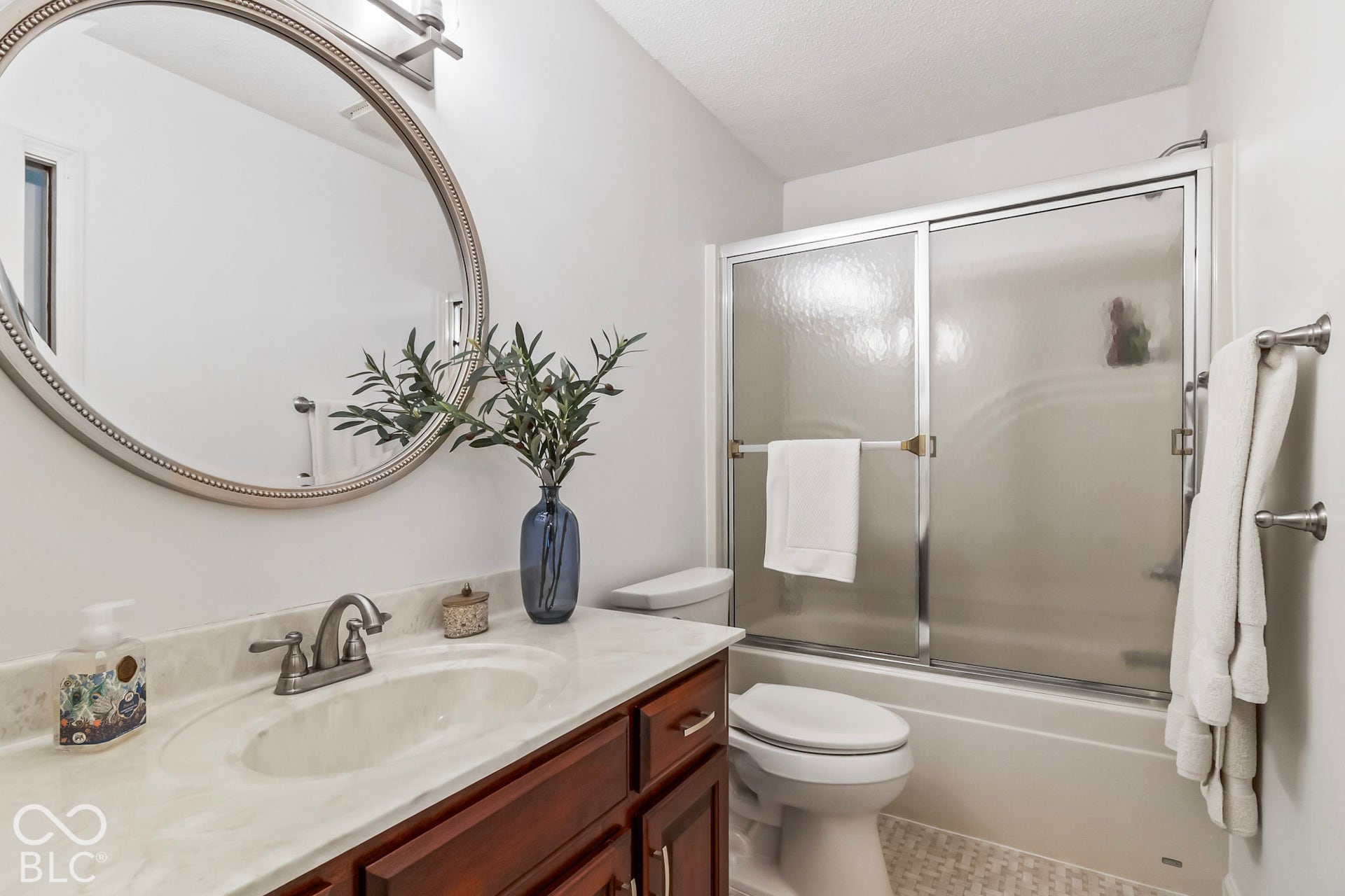 10954 N County Road 150 Road E, Pittsboro, IN 46167 Bathroom featuring a wooden vanity with a stone-finish countertop, oval undermount sink, brushed nickel hardware, and a round wall-mounted mirror