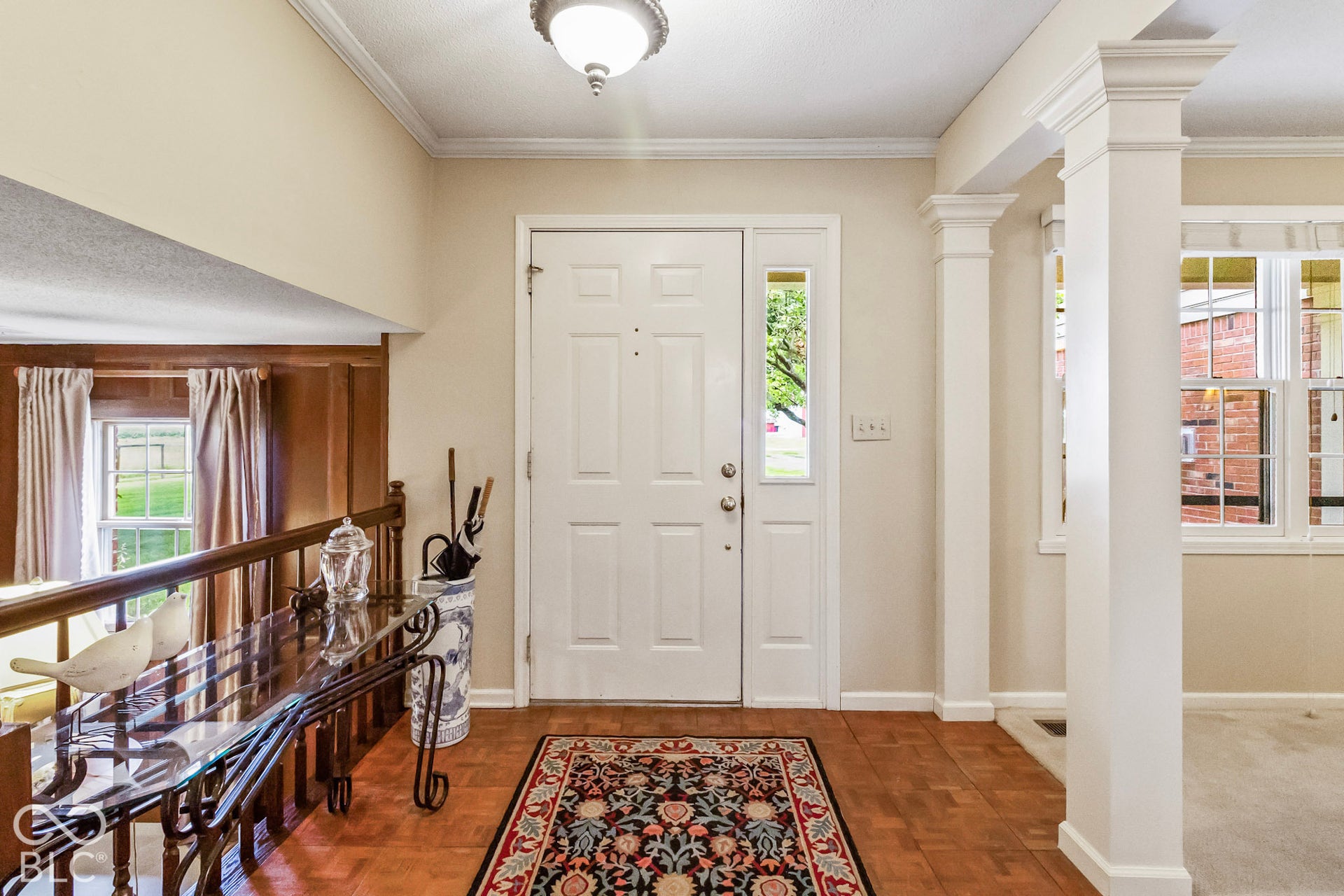 10954 N County Road 150 Road E, Pittsboro, IN 46167 Entryway featuring wood-finish parquet flooring, a paneled front door with a side light, decorative architectural columns, and wood-paneled wall accents
