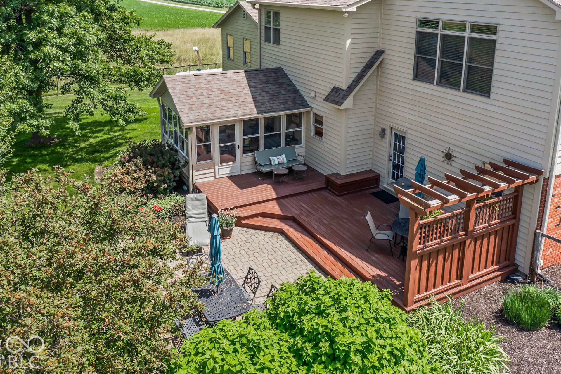 10954 N County Road 150 Road E, Pittsboro, IN 46167 Multi-level wood deck featuring a built-in pergola, brick paver patio, and enclosed sunroom