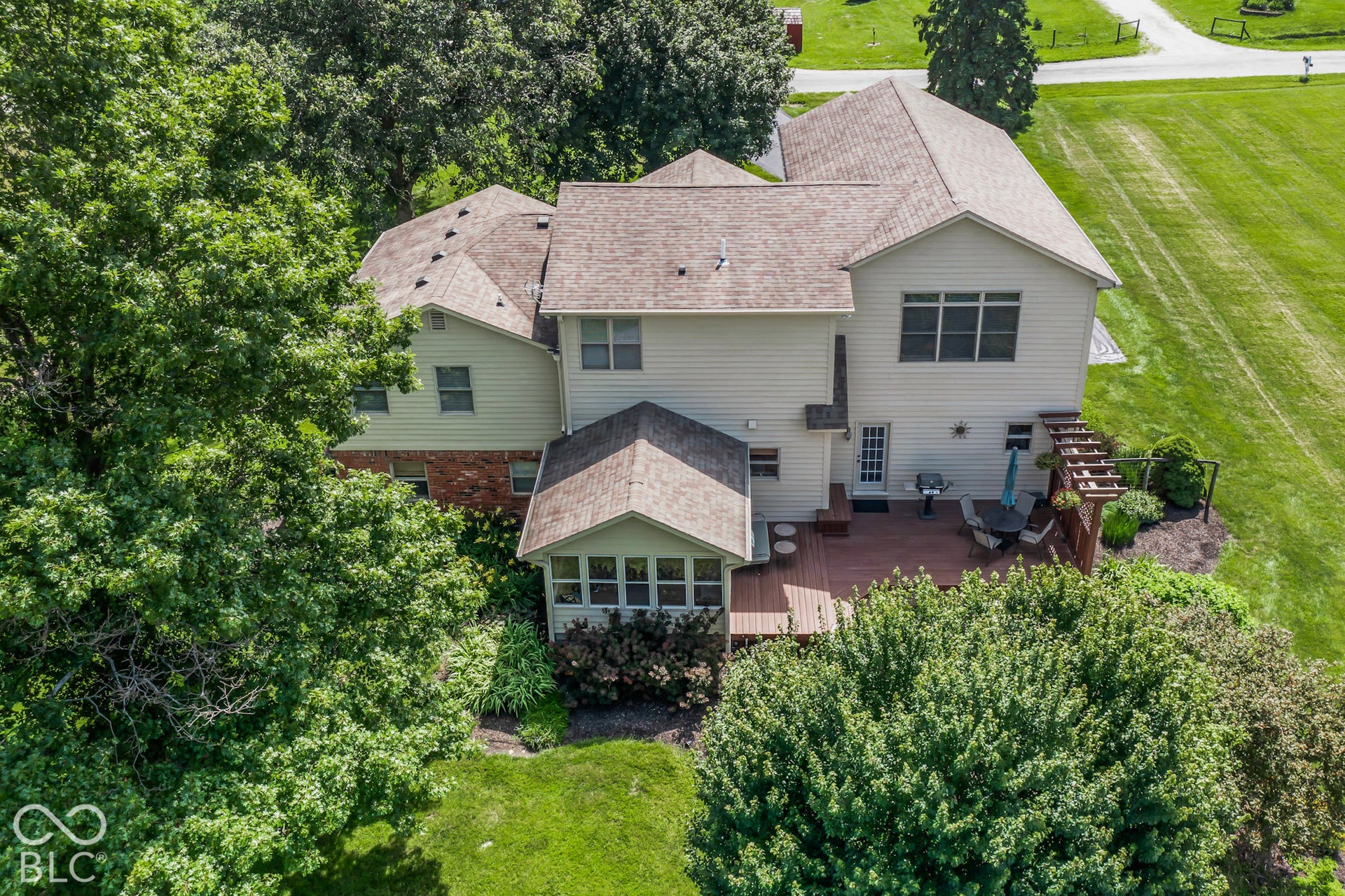 10954 N County Road 150 Road E, Pittsboro, IN 46167 Two-story residence featuring light-colored siding, a shingled roof, a ground-level wood deck, a covered sunroom, and a wood pergola