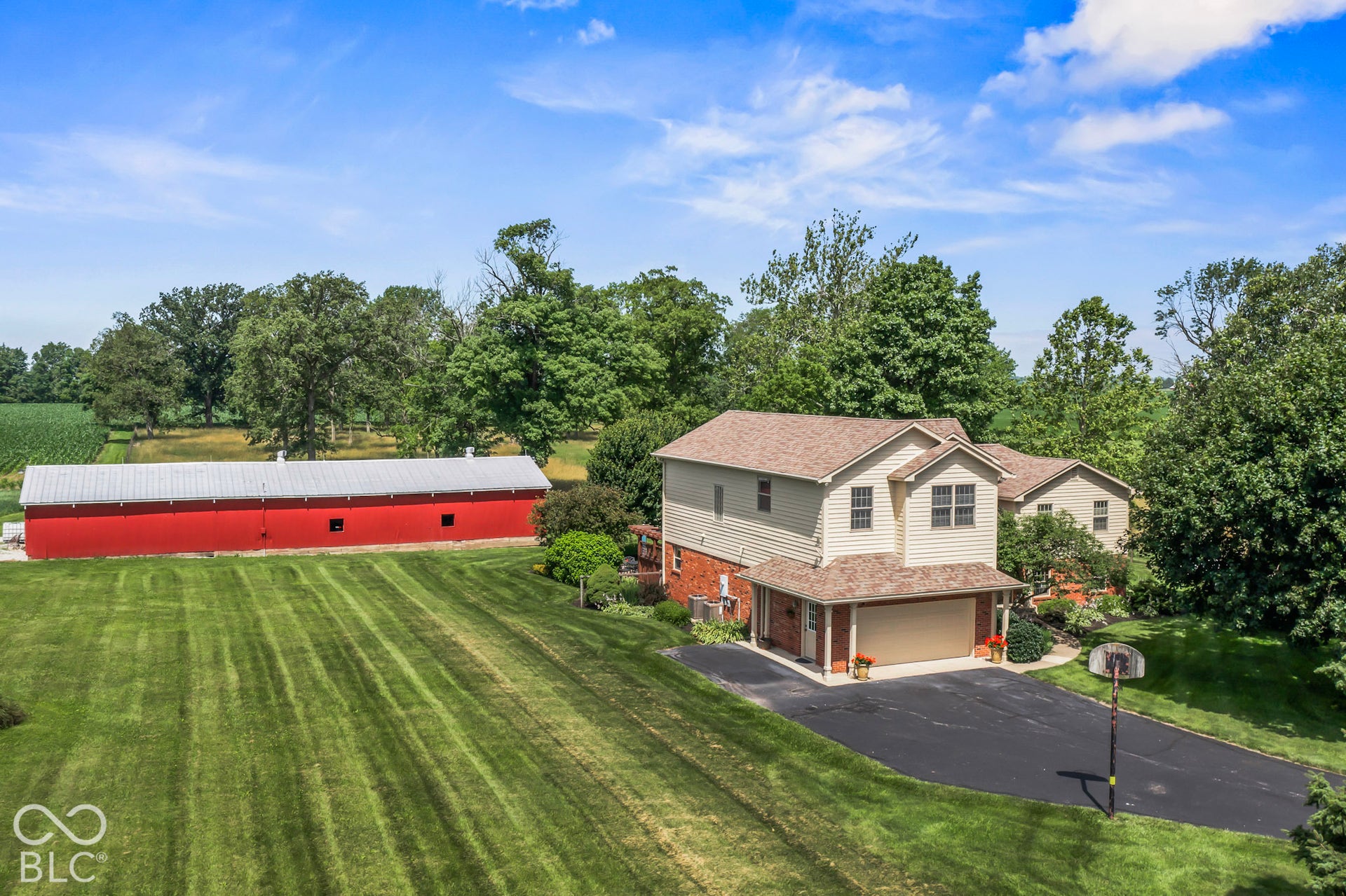 10954 N County Road 150 Road E, Pittsboro, IN 46167 Two-story residence with a multi-material exterior featuring siding and brick accents, attached garage, expansive grounds, and a detached metal-roofed barn