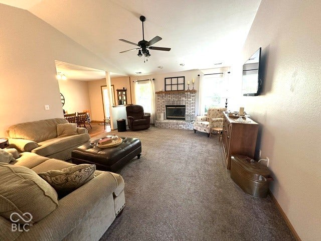 1712 Austin Drive, Lebanon, IN 46052 Vaulted ceiling with an attached ceiling fan, brick fireplace with a mantel, and gray carpeted flooring