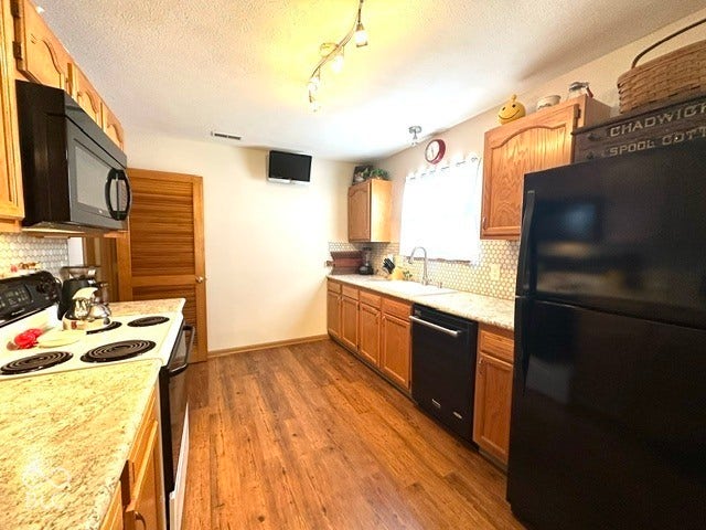 1712 Austin Drive, Lebanon, IN 46052 Wood-finish flooring, light wood cabinetry, white honeycomb tile backsplash, and light-toned countertops