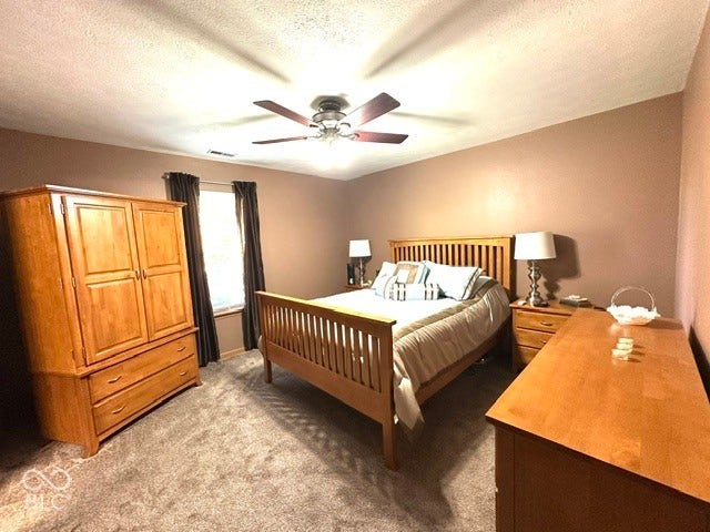 1712 Austin Drive, Lebanon, IN 46052 Textured carpeting, window with dark drapes, ceiling fan with integrated lighting, and neutral wall tones