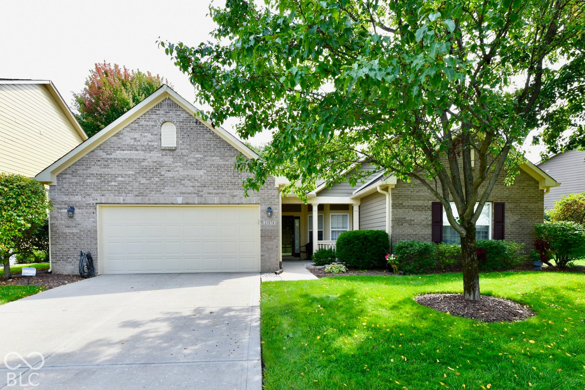 Brick and siding exterior with an attached garage, covered front entry, and mature landscaping