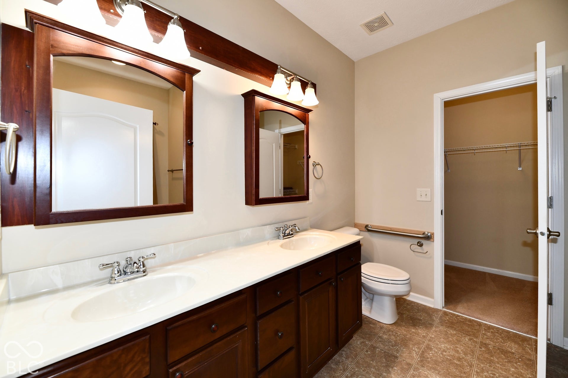 Dual vanity with wood-finish cabinetry, integrated sinks, and polished chrome fixtures