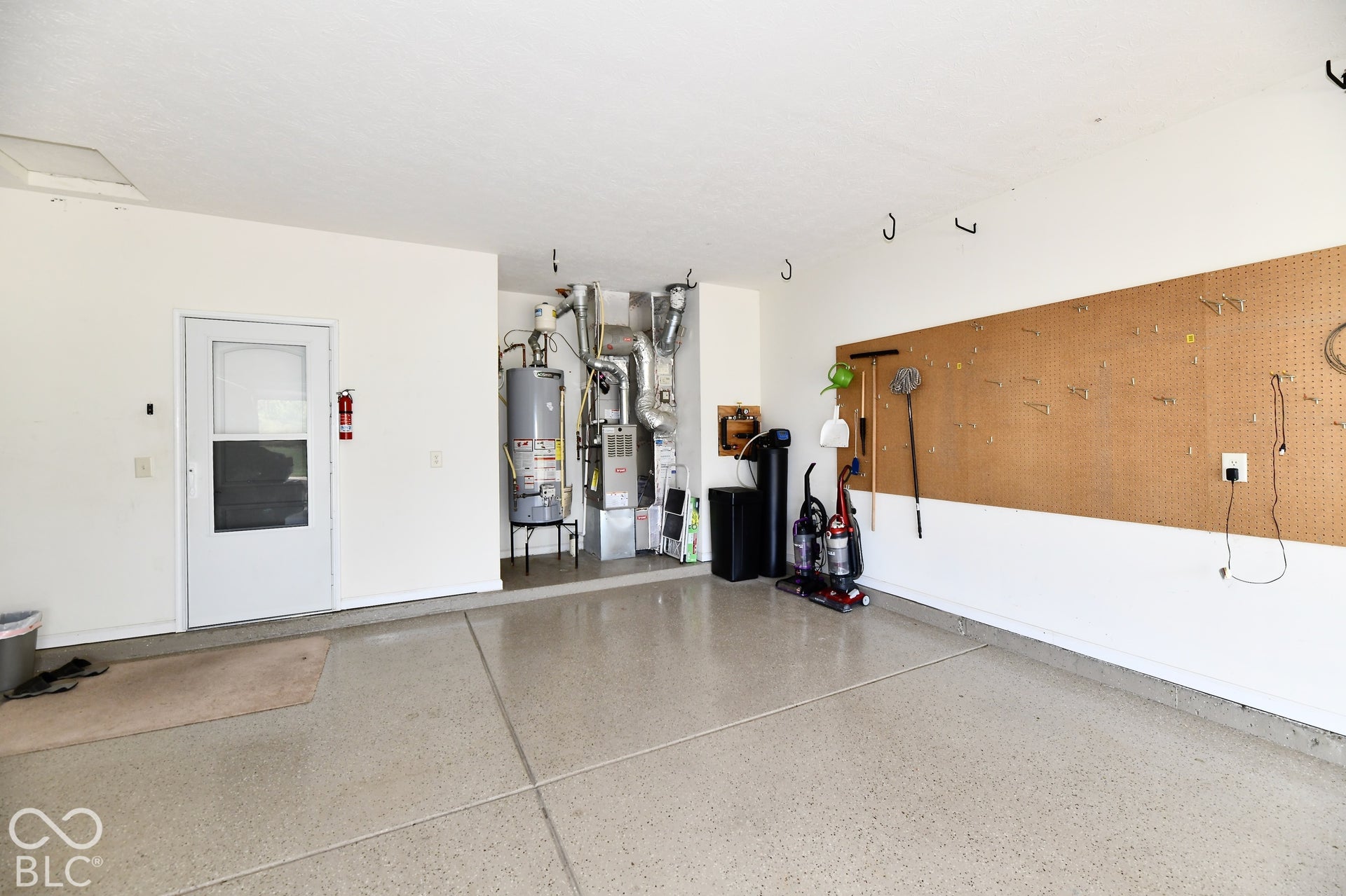 Epoxy-coated concrete flooring, water heater, water softener, and a large pegboard wall