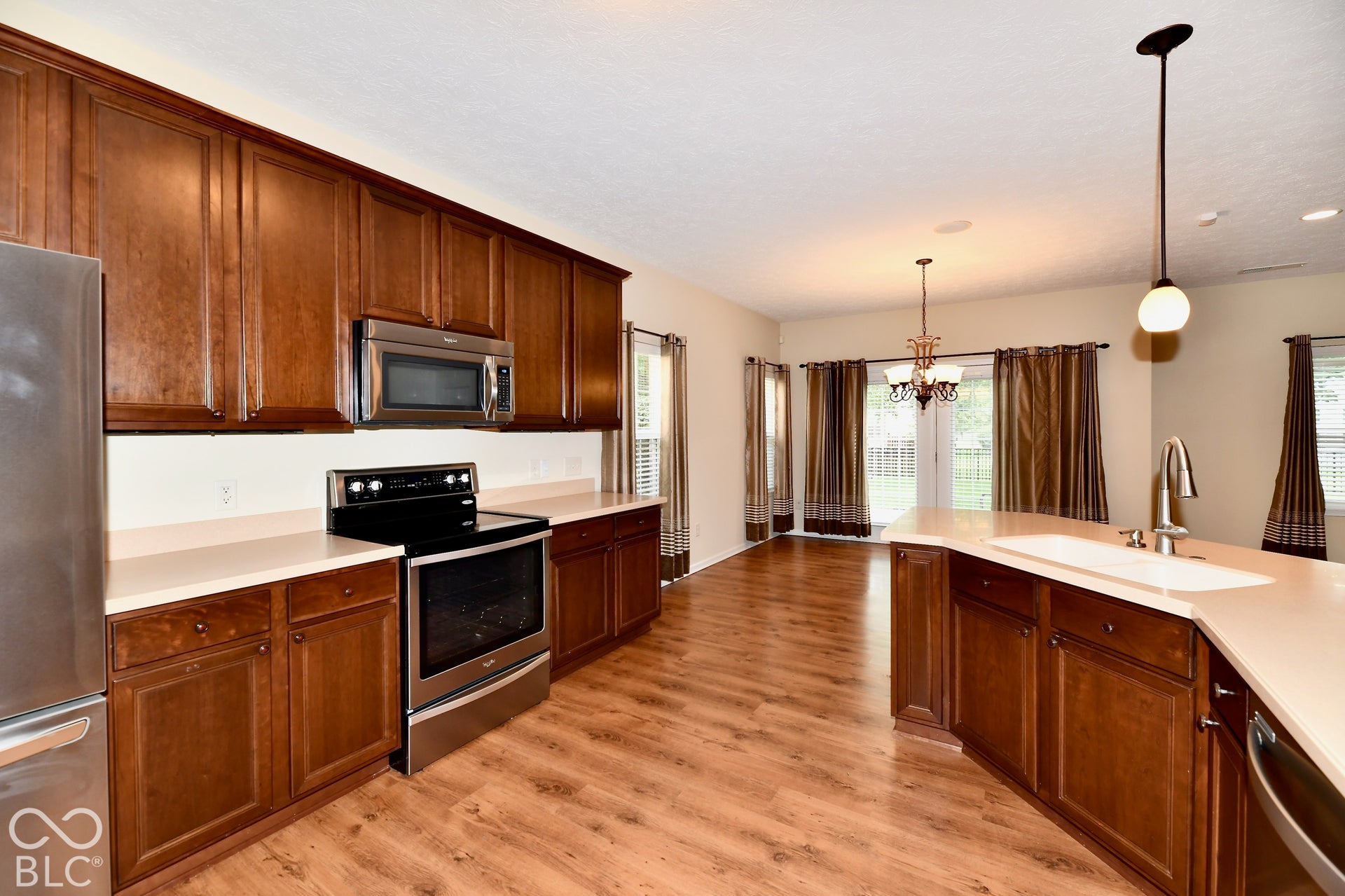 Kitchen featuring stainless steel appliances, wood-finish flooring, recessed lighting, and a kitchen island with an integrated sink