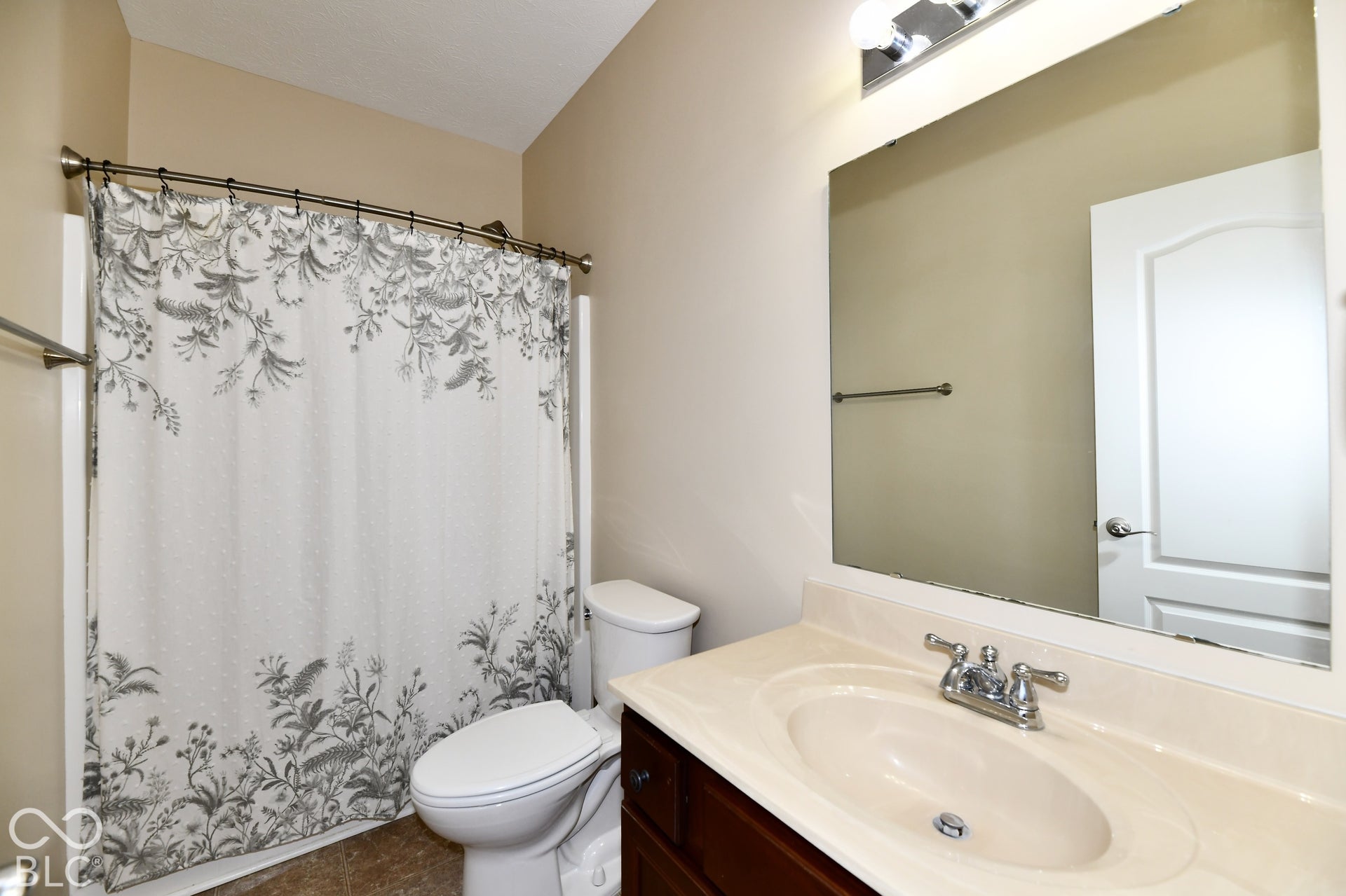 Bathroom featuring a single vanity with a laminate countertop, built-in sink, and chrome faucet