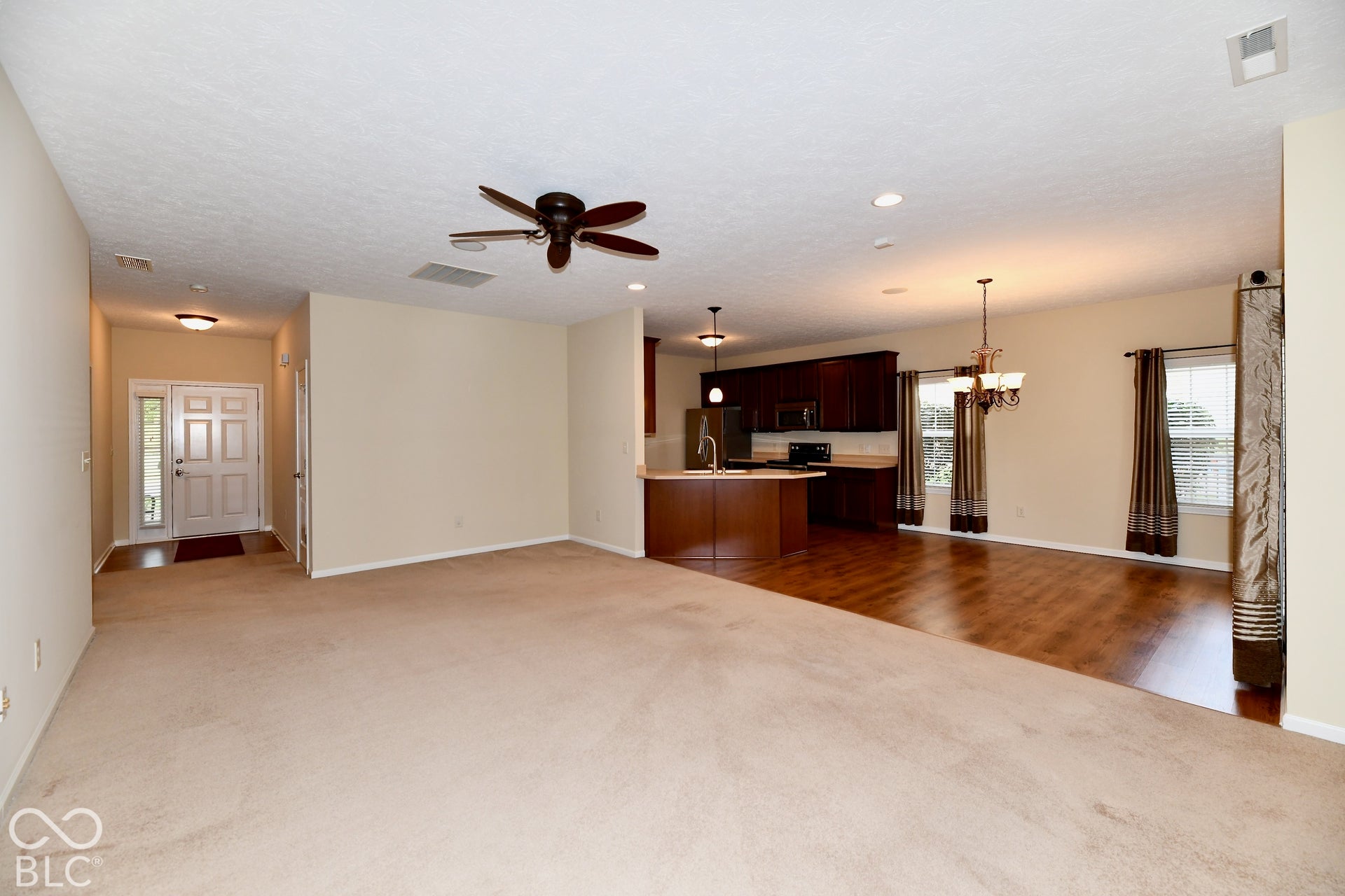Spacious living area featuring carpet flooring, a ceiling fan, and recessed lighting