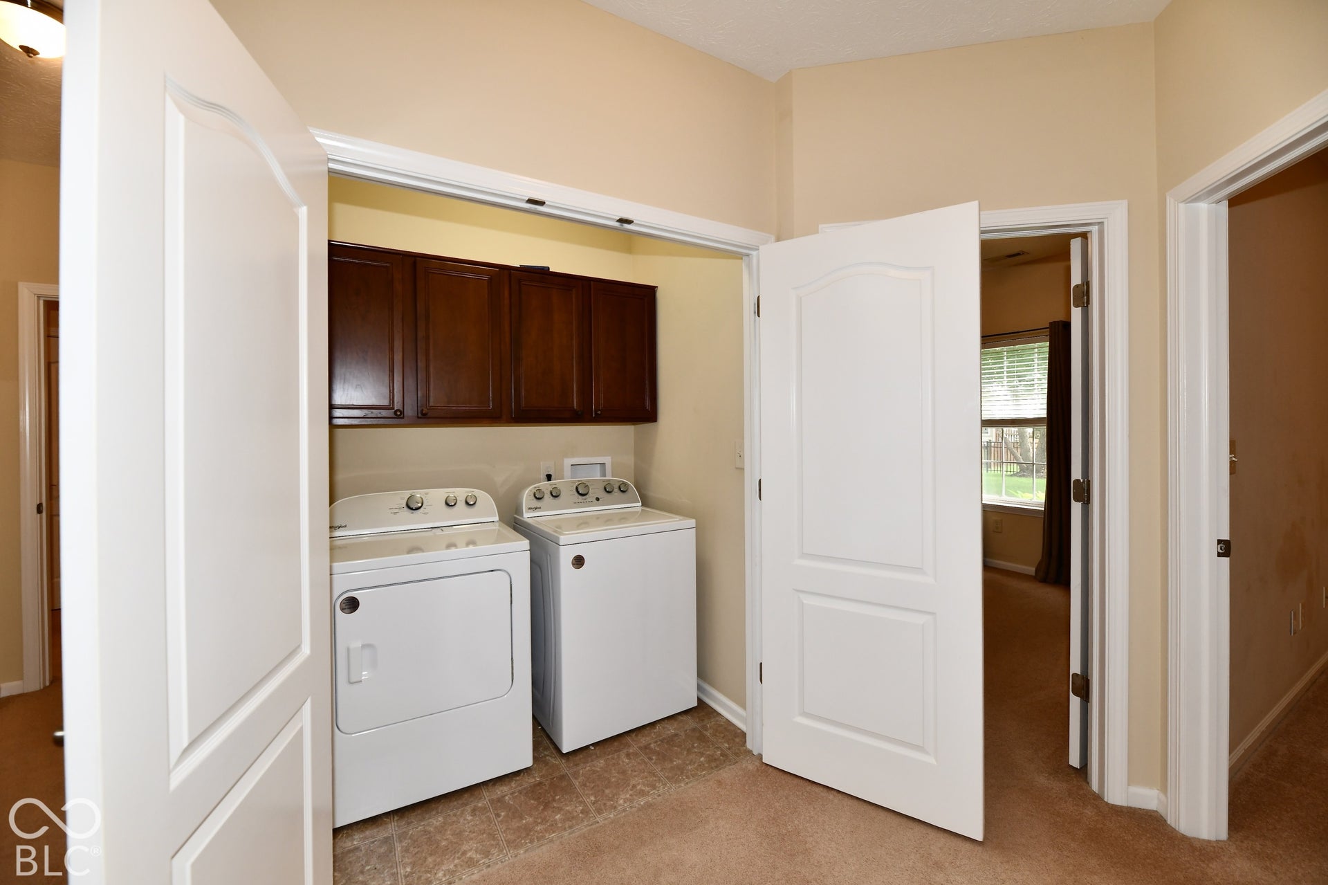 Laundry closet with wood-finish cabinetry and vinyl flooring conveniently located in the hall near the bedrooms