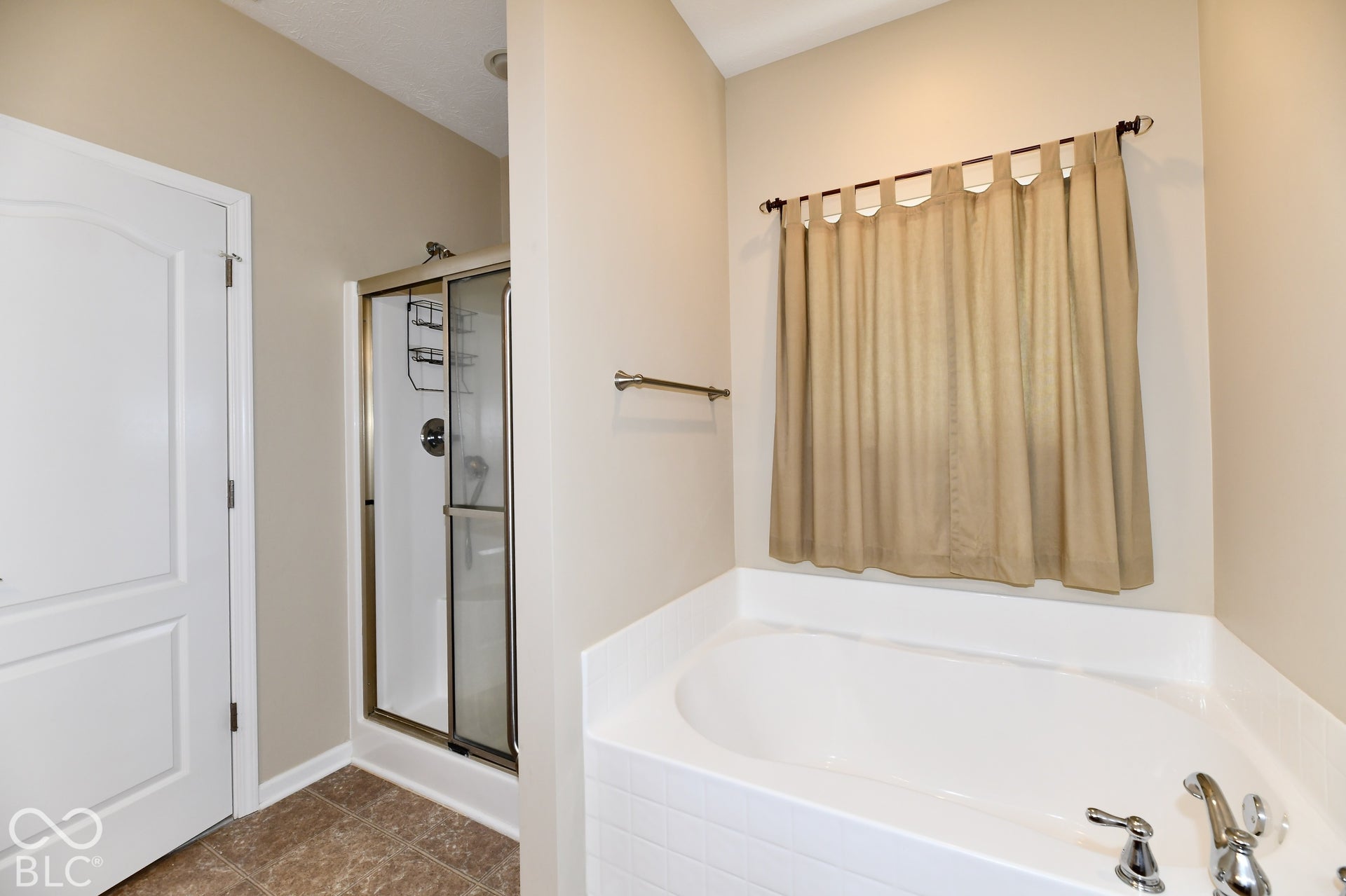 Walk-in shower with clear glass enclosure, built-in soaking tub, and tile flooring