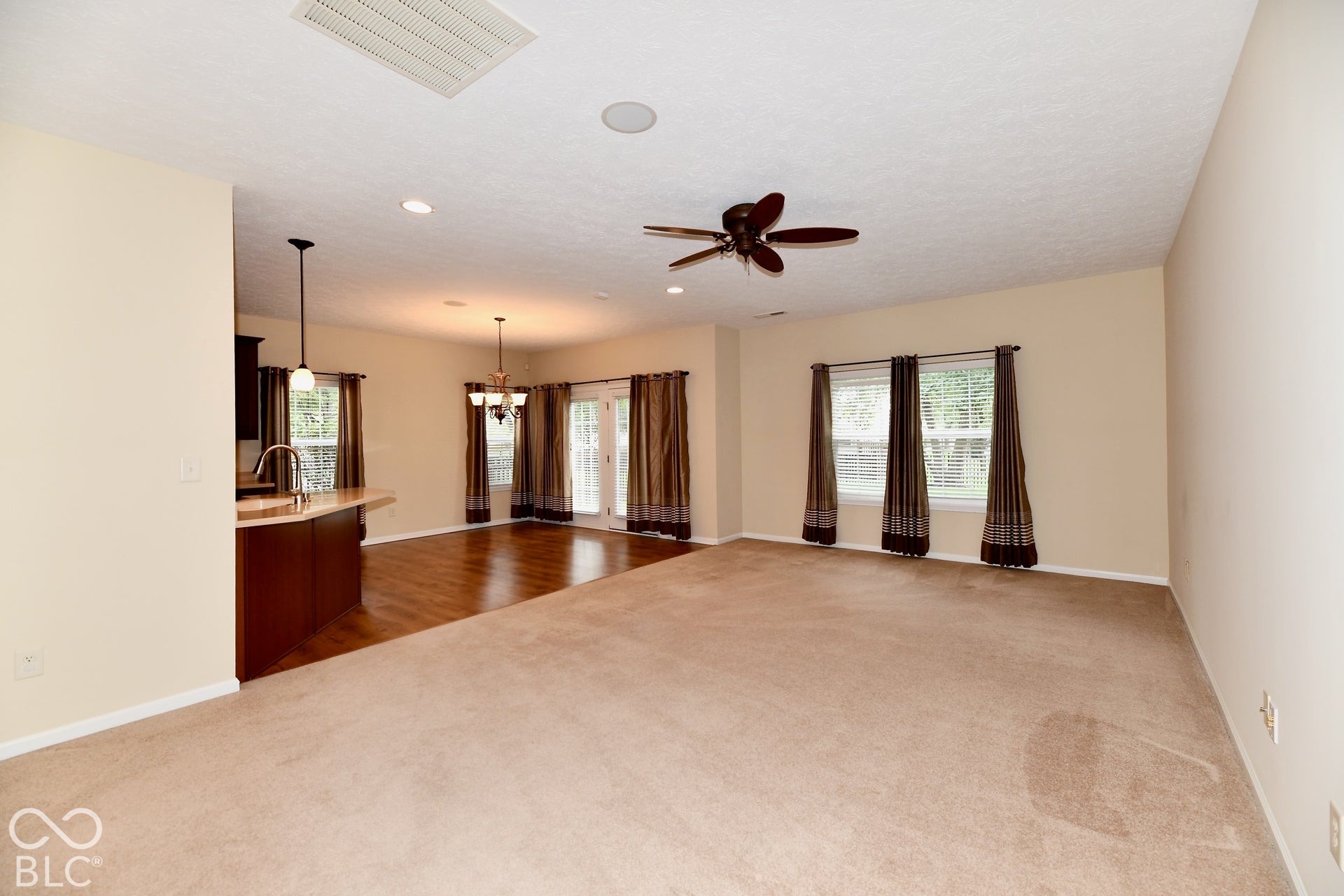 Expansive open-concept room with carpet flooring, ceiling fan, and recessed lighting