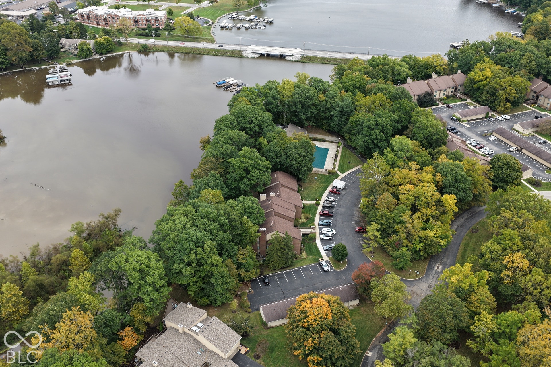 201 Bluffs Circle, Noblesville, IN 46062 Waterfront property with extensive mature trees, multiple parking areas, and an outdoor swimming pool