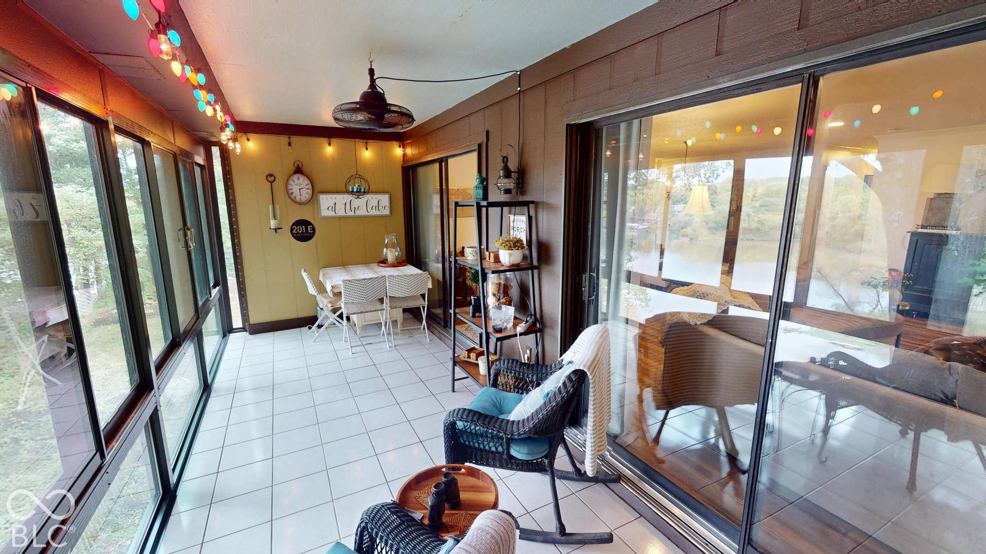 201 Bluffs Circle, Noblesville, IN 46062 Enclosed porch with full-height windows, white tile flooring, wood-paneled walls, and a ceiling fan light fixture