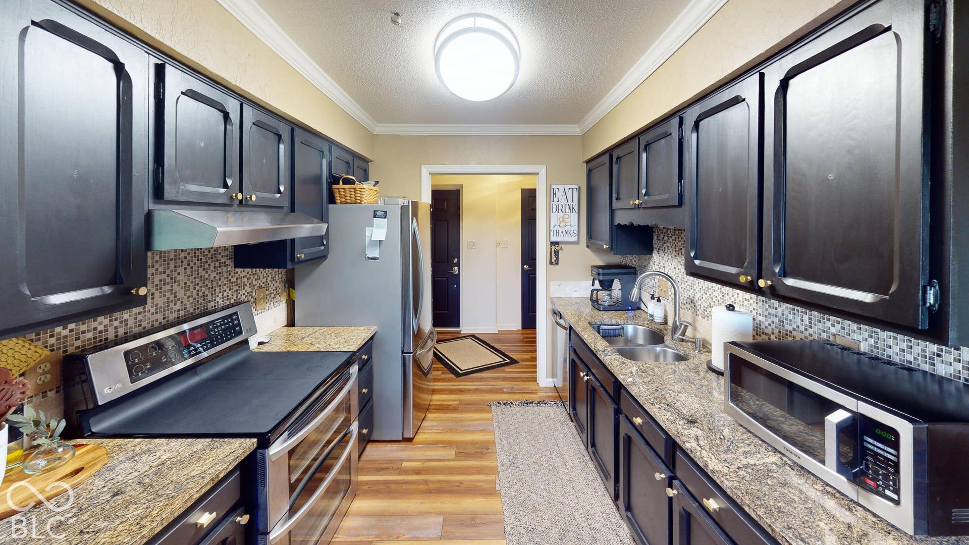 201 Bluffs Circle, Noblesville, IN 46062 Kitchen featuring wood-finish flooring, dark cabinetry, and stone countertops