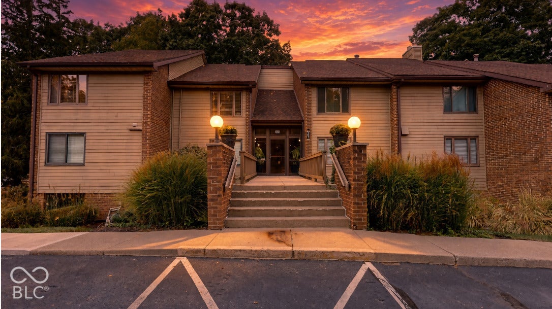 201 Bluffs Circle, Noblesville, IN 46062 Virtually Altered - Multi-story building featuring tan siding, brick accents, and a central entrance with steps and handrails