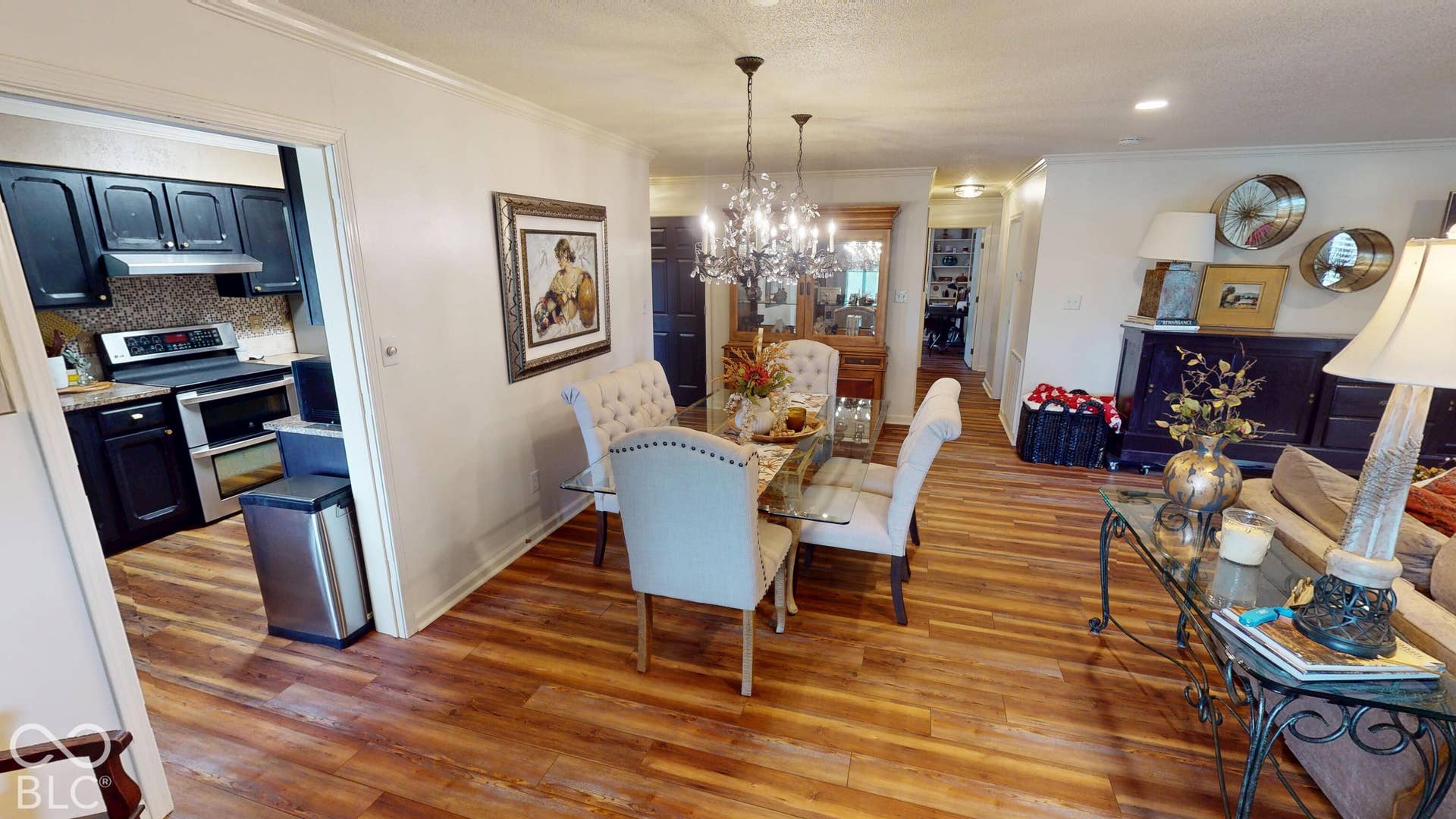 201 Bluffs Circle, Noblesville, IN 46062 Wood-finish flooring throughout, framed opening to kitchen with black cabinetry, stainless steel oven, and mosaic tile backsplash
