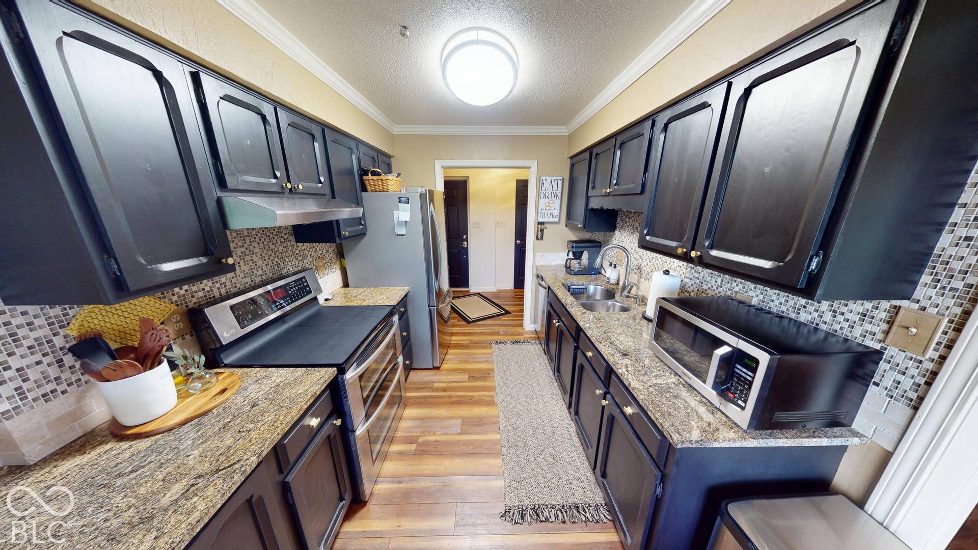 201 Bluffs Circle, Noblesville, IN 46062 Galley kitchen featuring dark wood-finish cabinetry, granite-style countertops, mosaic tile backsplash, and wood-finish flooring