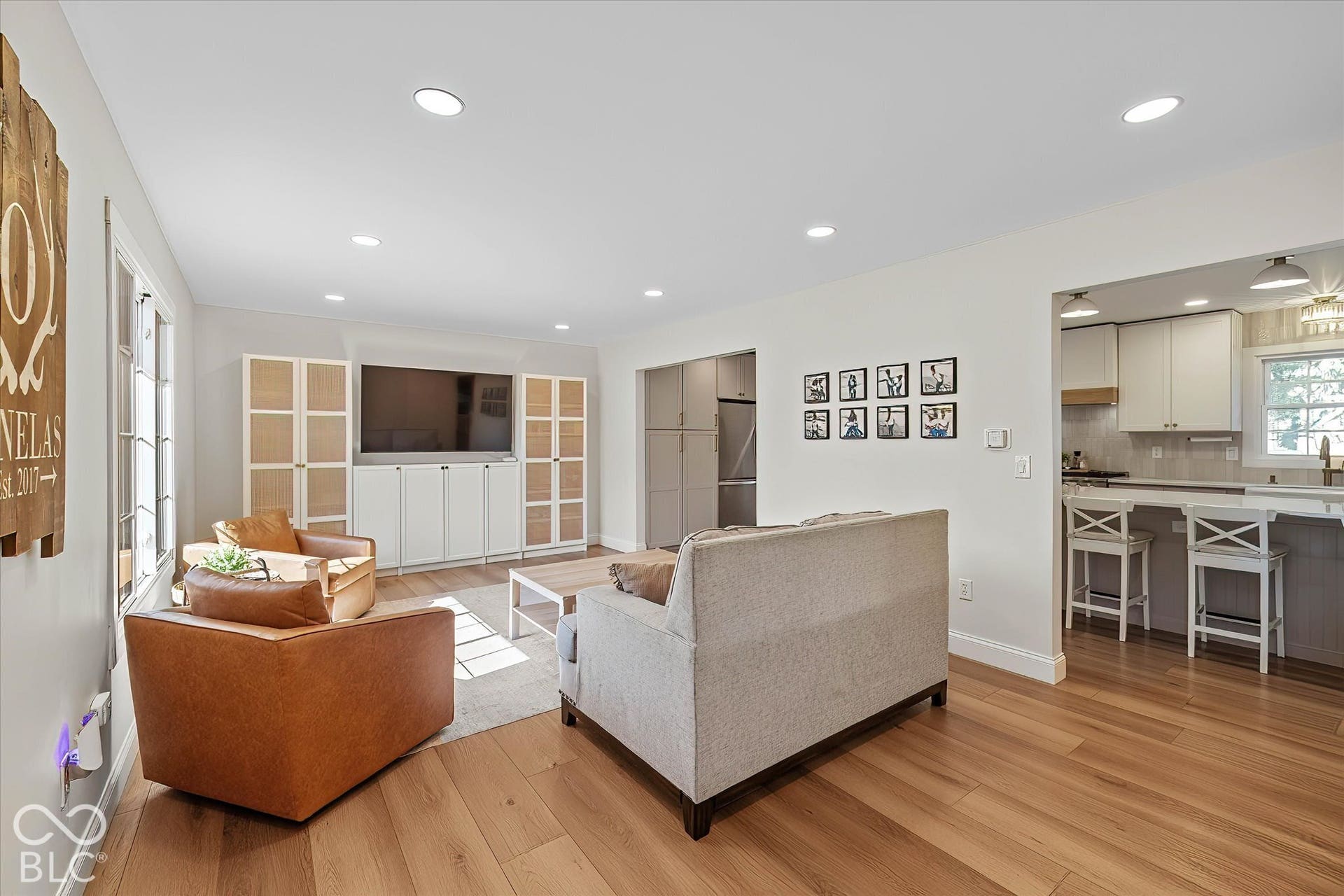 Living room w/ wide plank LVP flooring and stunning built-in shelving unit. Open to kitchen.