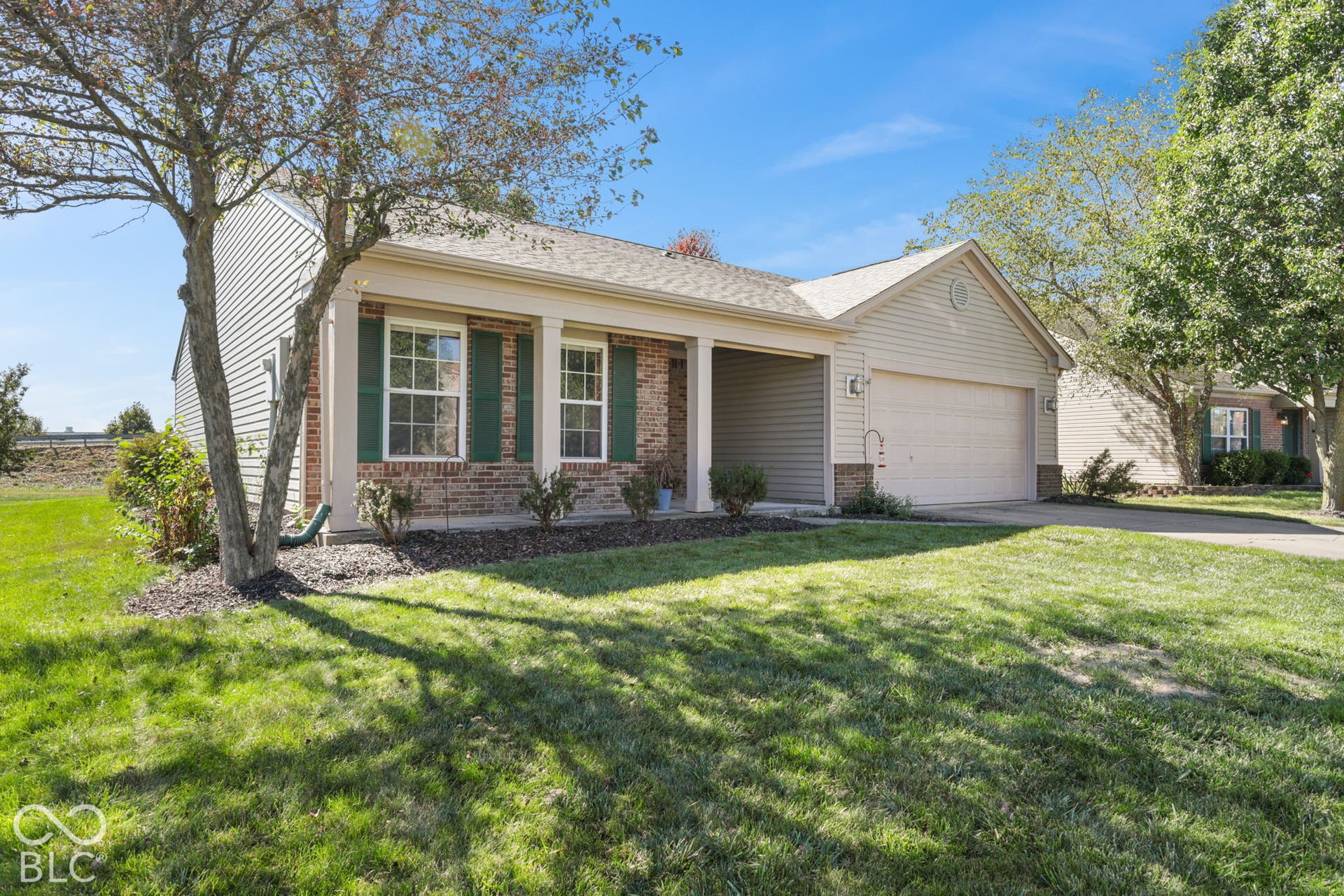 Brick and siding exterior with a covered porch entry, attached two-car garage, and a concrete driveway